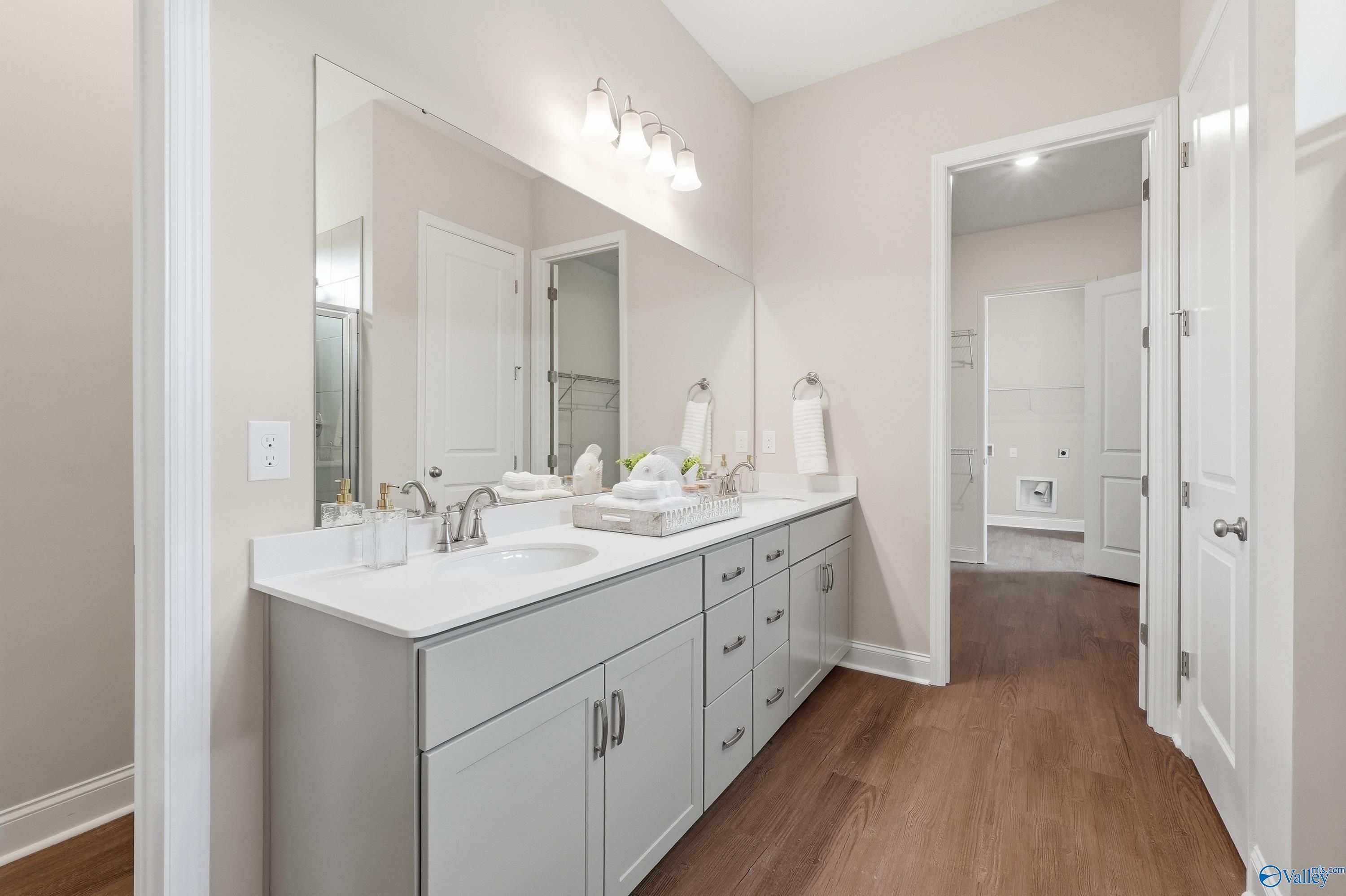 Modern double vanity in master bathroom with gray shaker cabinets, white quartz counters, and large mirror in Davidson Homes The Arcadia B, Huntsville