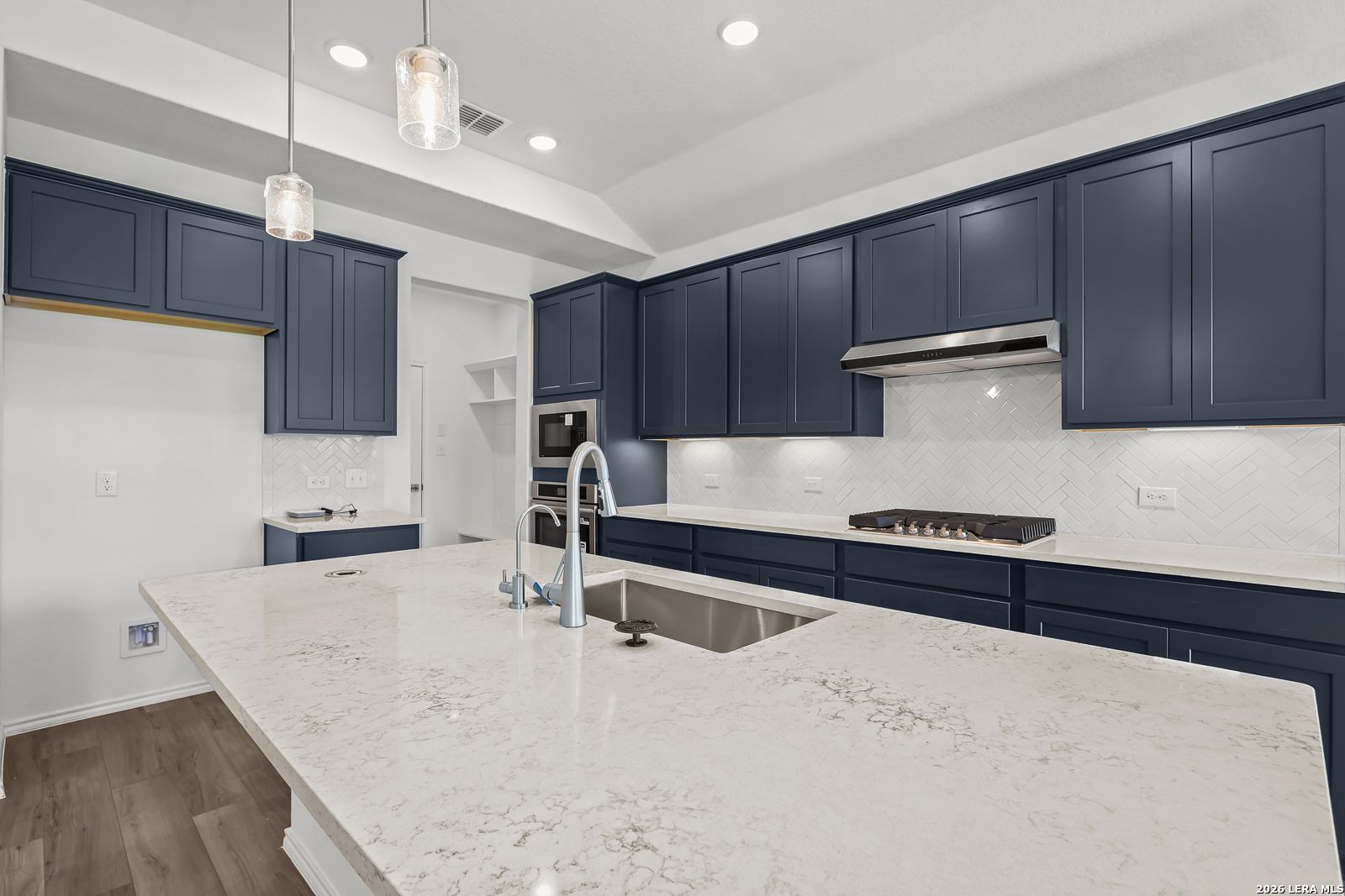 Modern navy blue kitchen with white quartz island, stainless appliances in Davidson Homes The Sequoia B, San Antonio