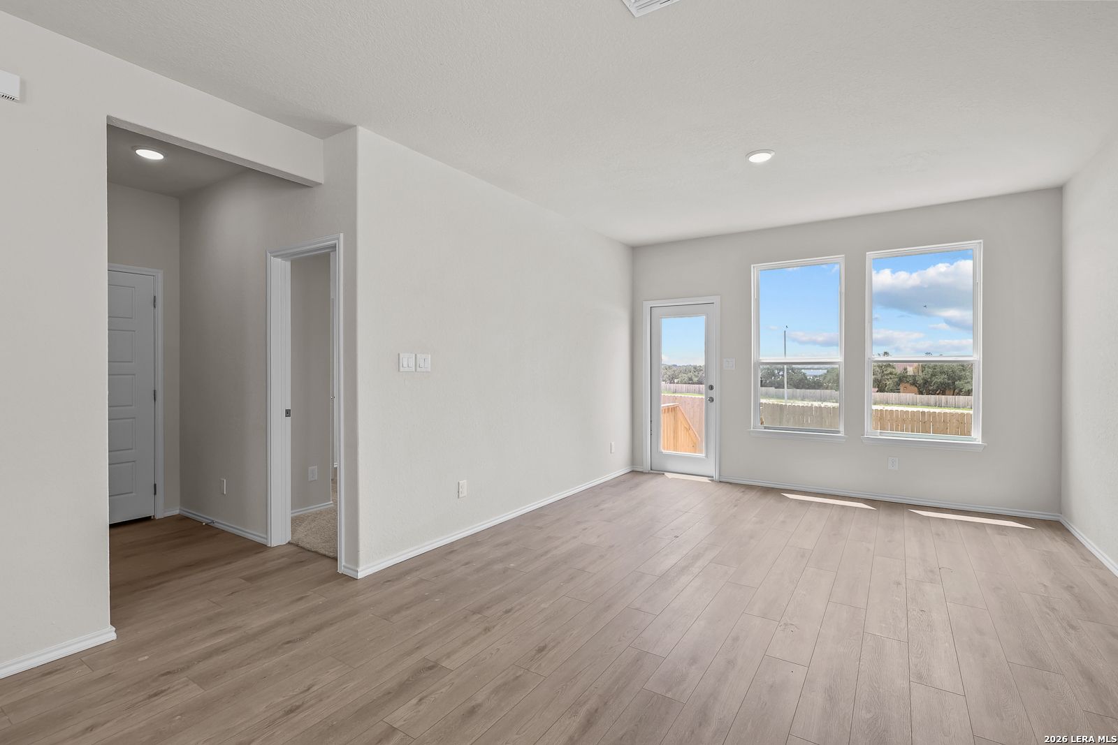 Bright living area with wood-style flooring in The Gillian B floor plan at Meadows at Oak Creek, San Antonio, Texas.