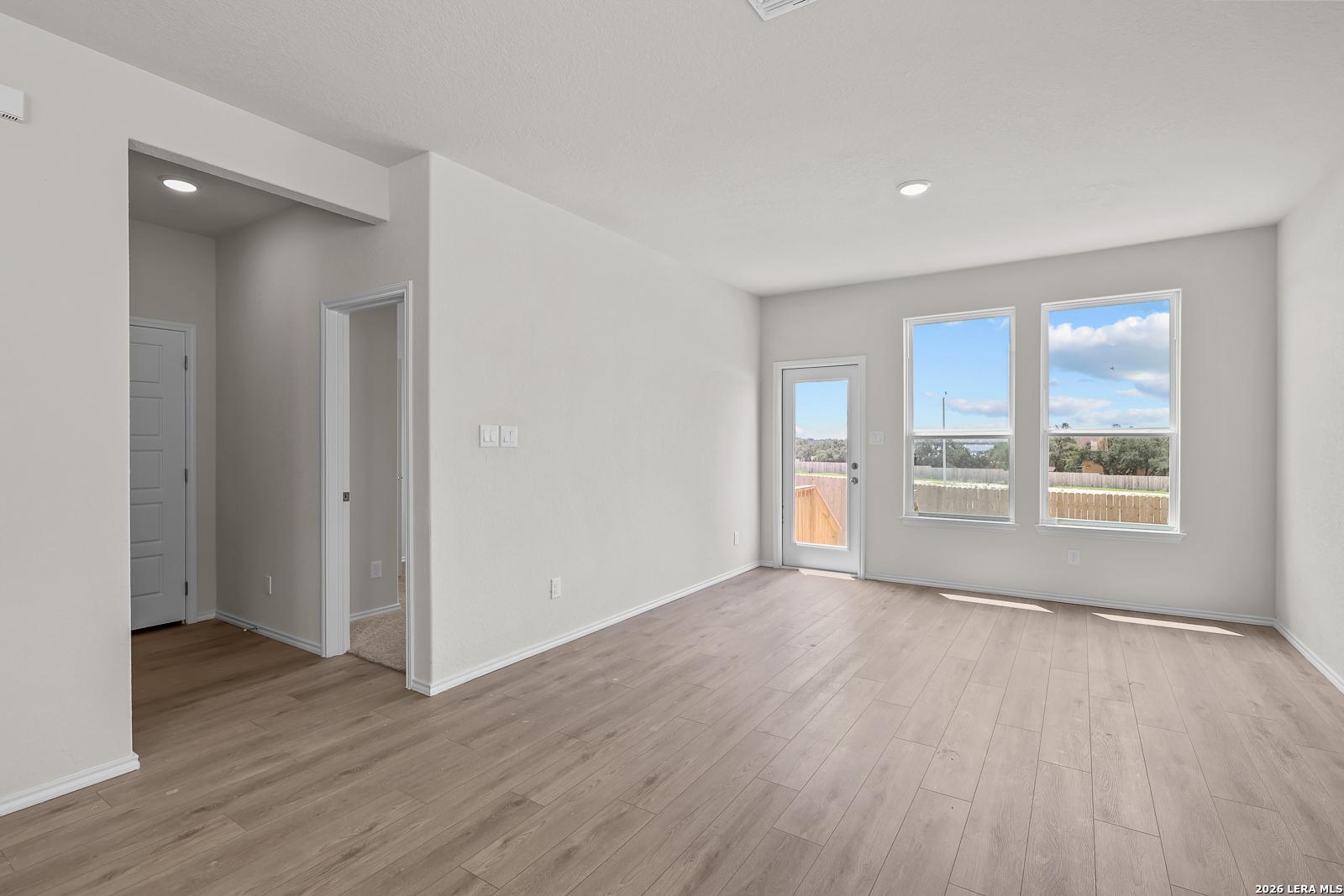 Bright living area with wood-style flooring in The Gillian B floor plan at Meadows at Oak Creek, San Antonio, Texas.