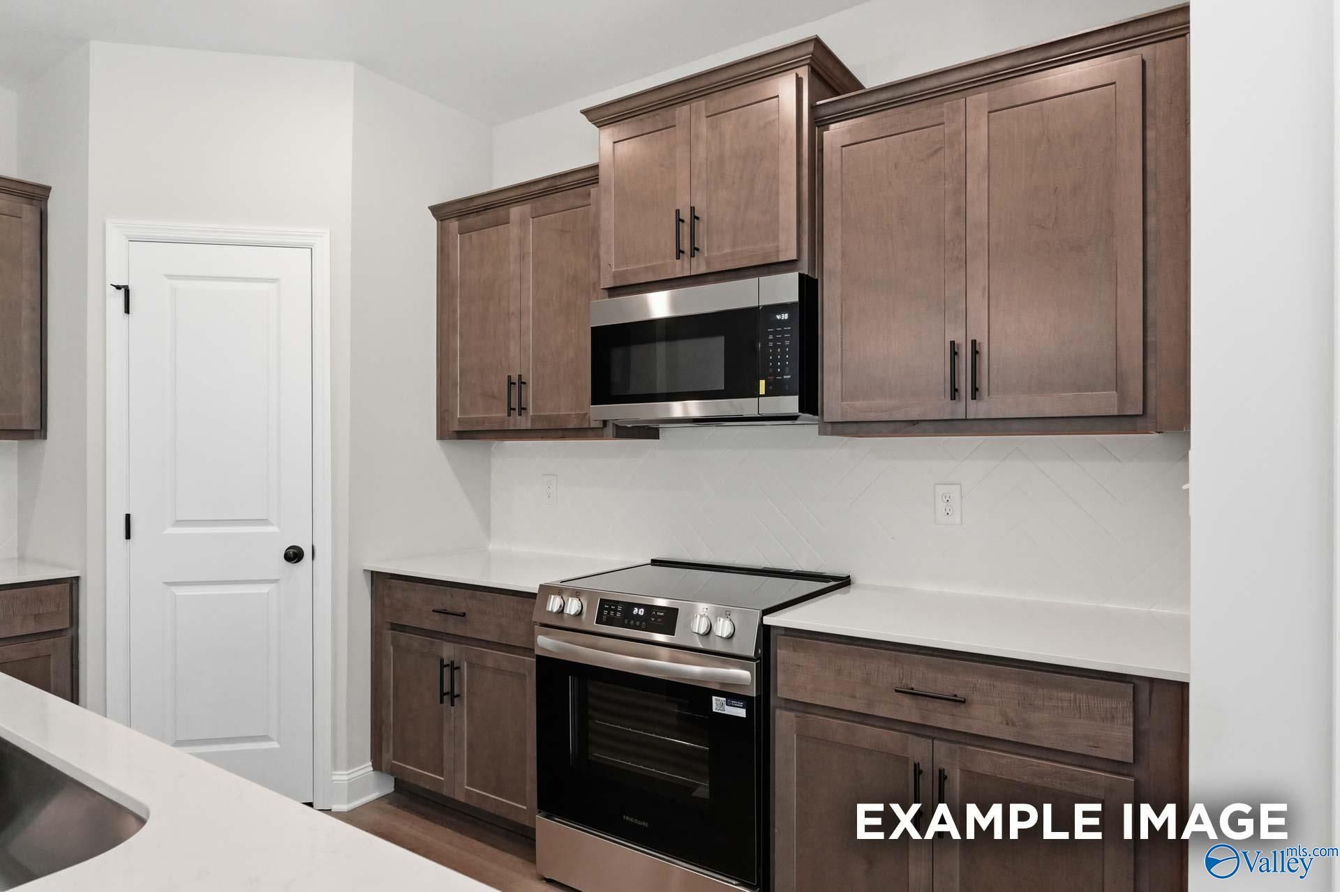 Modern kitchen with dark wood cabinets and stainless steel appliances in The Franklin C floor plan, Arab, Alabama home.