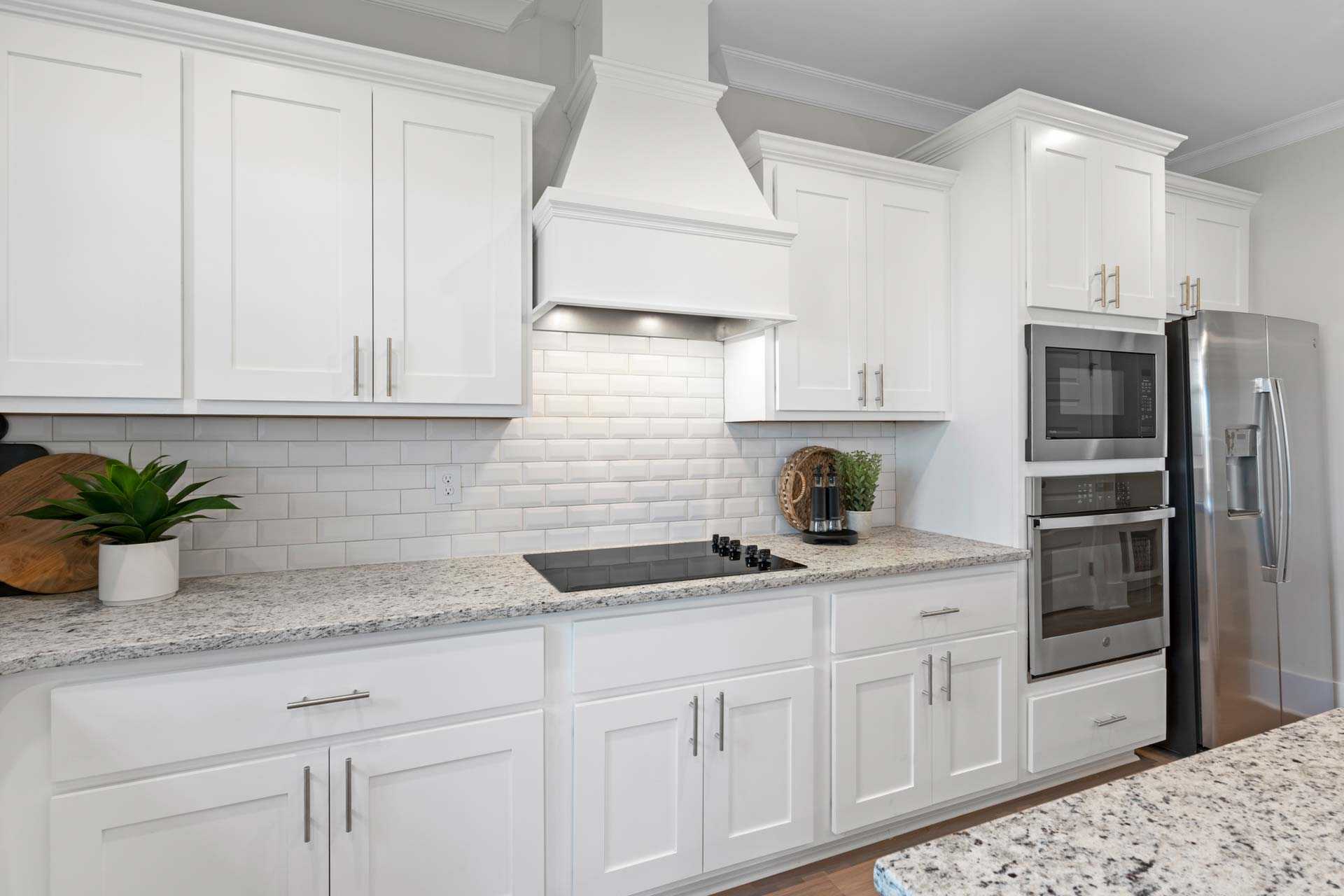 Modern kitchen featuring white shaker cabinets, subway tile backsplash, granite counters, stainless steel appliances at Walker's Hill in Meridianville, Alabama