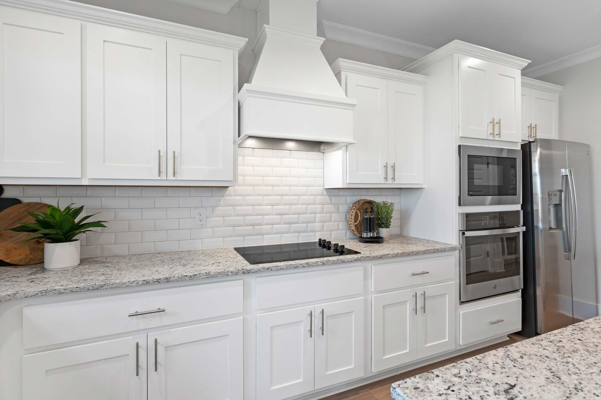 Modern kitchen featuring white shaker cabinets, subway tile backsplash, granite counters, stainless steel appliances at Walker's Hill in Meridianville, Alabama