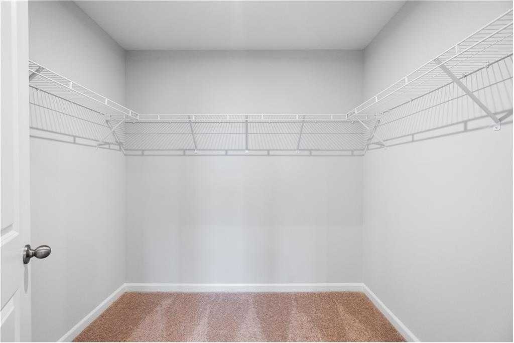 Spacious walk-in closet with wire shelving and beige carpet in Davidson Homes The Durant A, Stegall Village, Emerson, Georgia