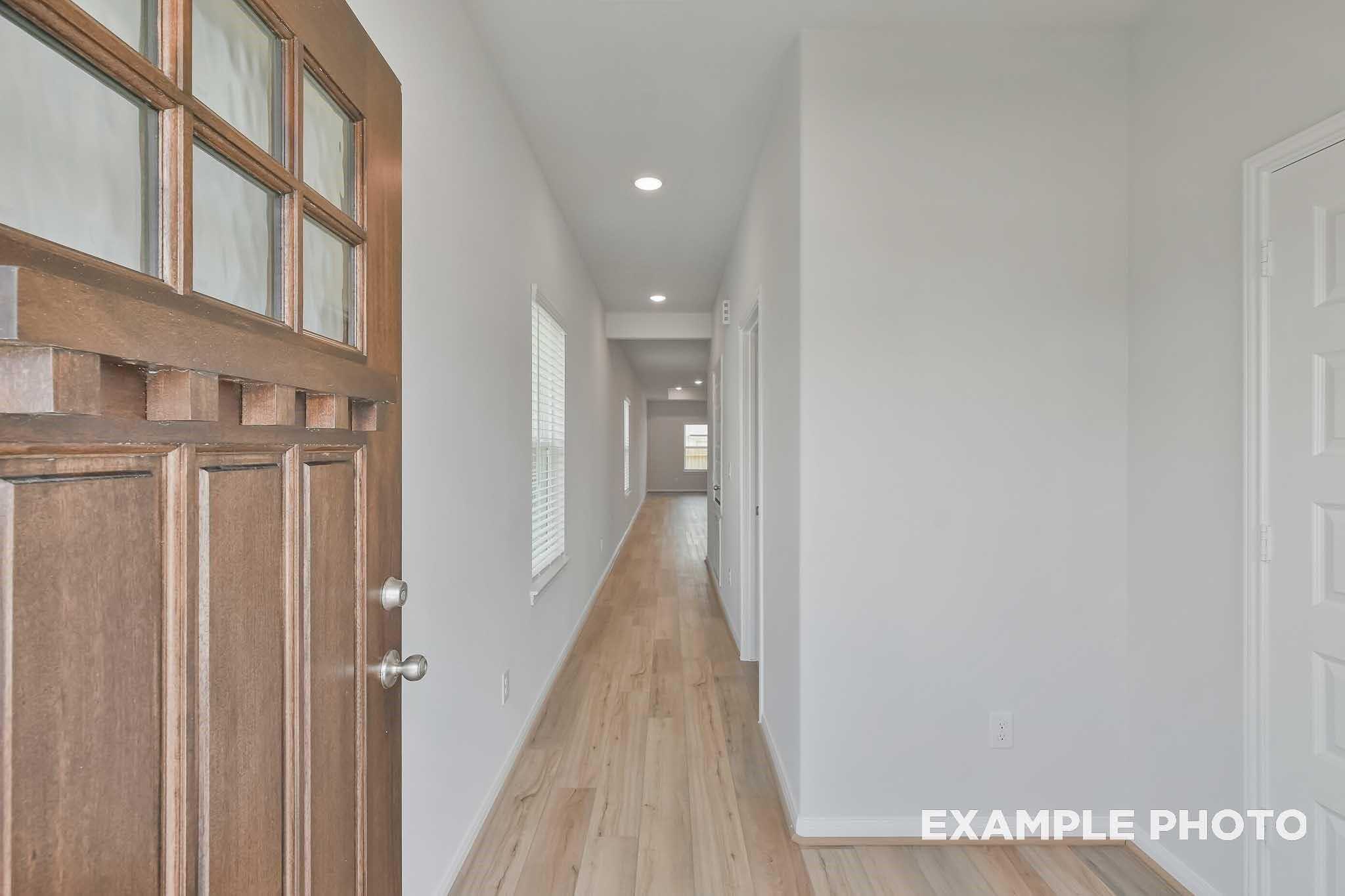 Welcoming entryway with wood door, hardwood floors and recessed lights in The Frio F 3-bedroom home, Conroe, Texas