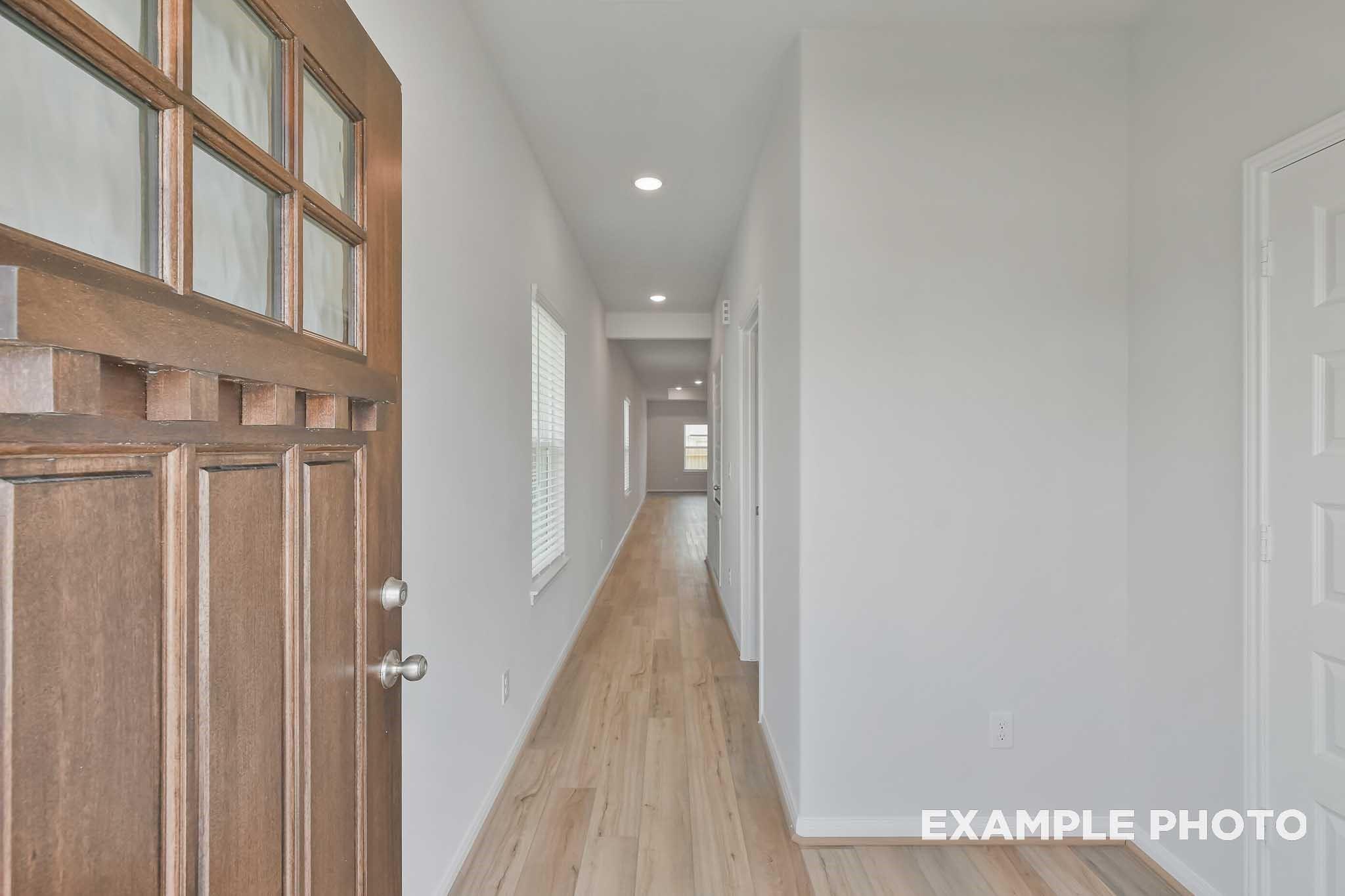 Welcoming entryway with wood door, hardwood floors and recessed lights in The Frio F 3-bedroom home, Conroe, Texas
