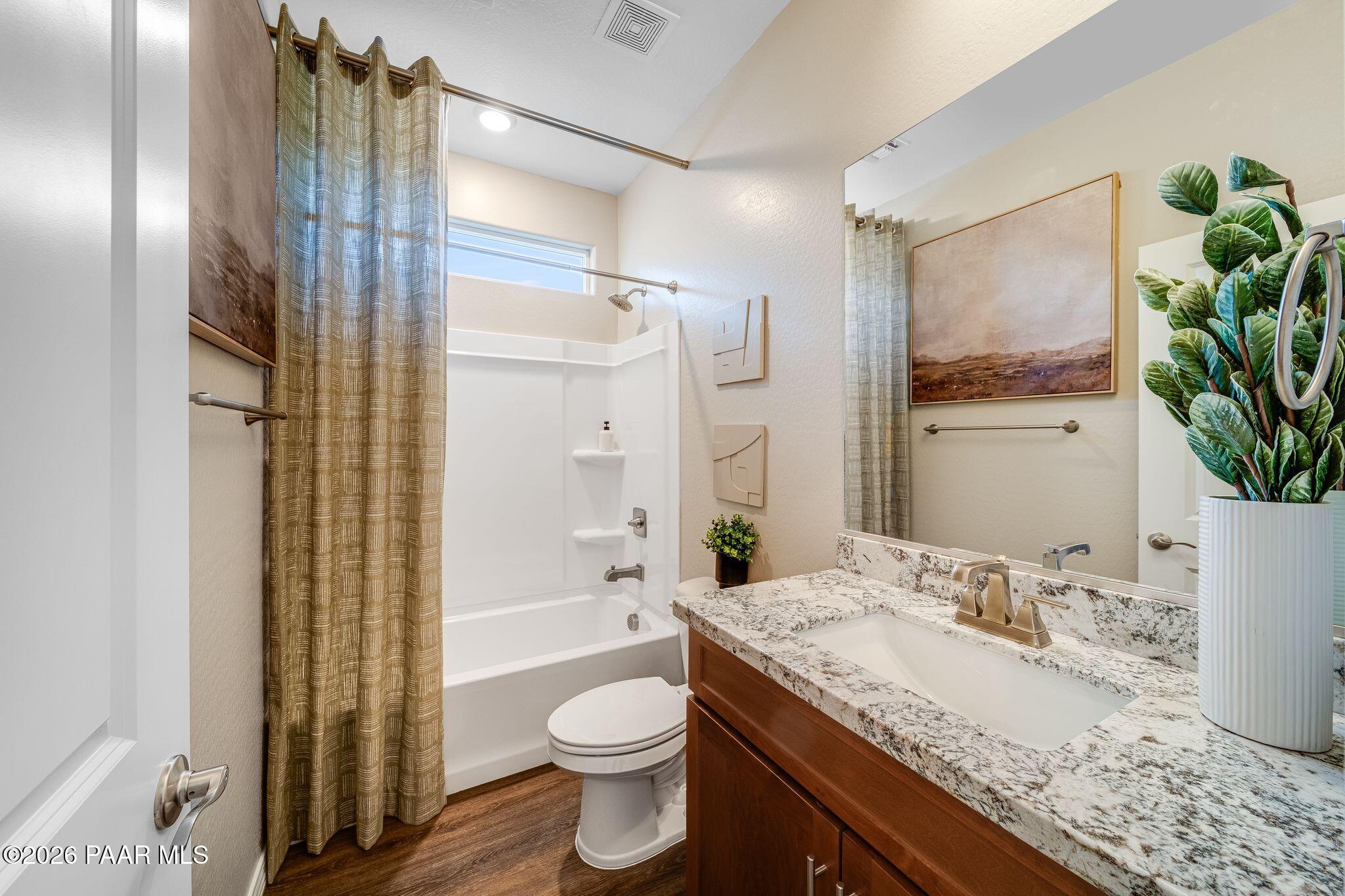 Modern bathroom with granite vanity, tub-shower combo, and wood-style flooring in Davidson Homes Savannah C, Prescott, AZ.