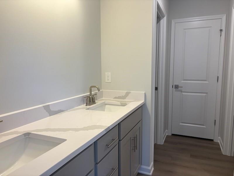 Modern double vanity with white quartz counters, gray cabinets, and chrome faucet in master bath of Davidson Homes The Rabun A, Winder GA