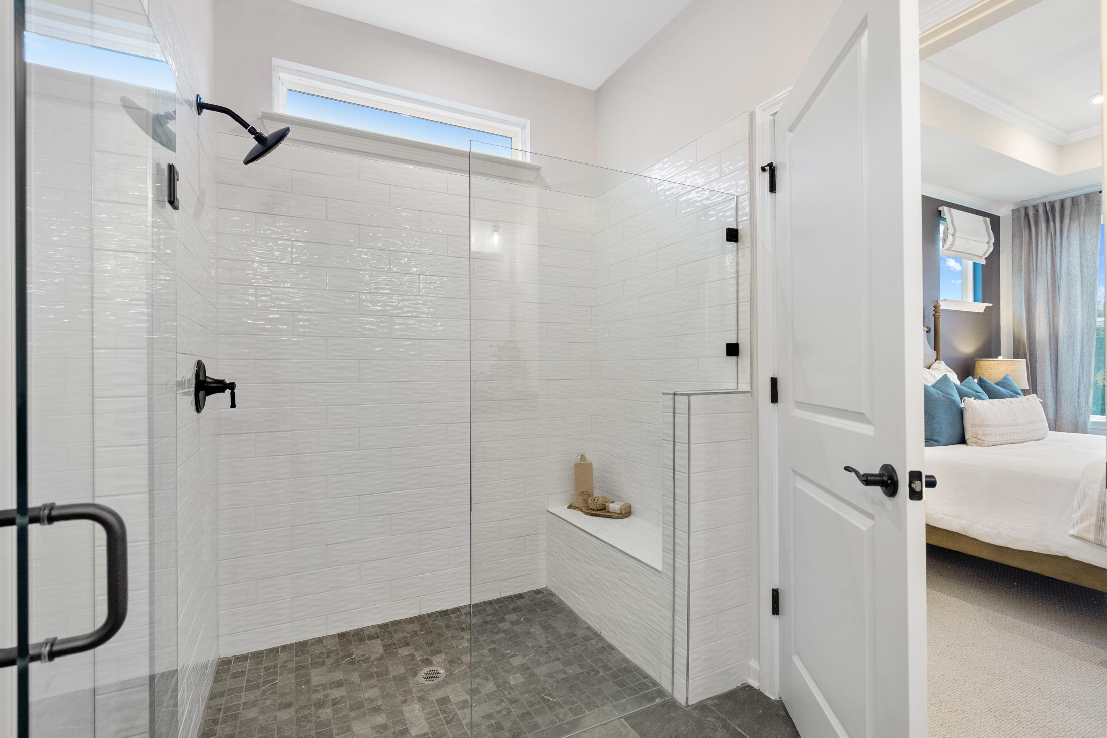 Spacious walk-in shower in primary bathroom at Kelly Preserve Loganville GA with white subway tiles, glass enclosure, and open door to bedroom