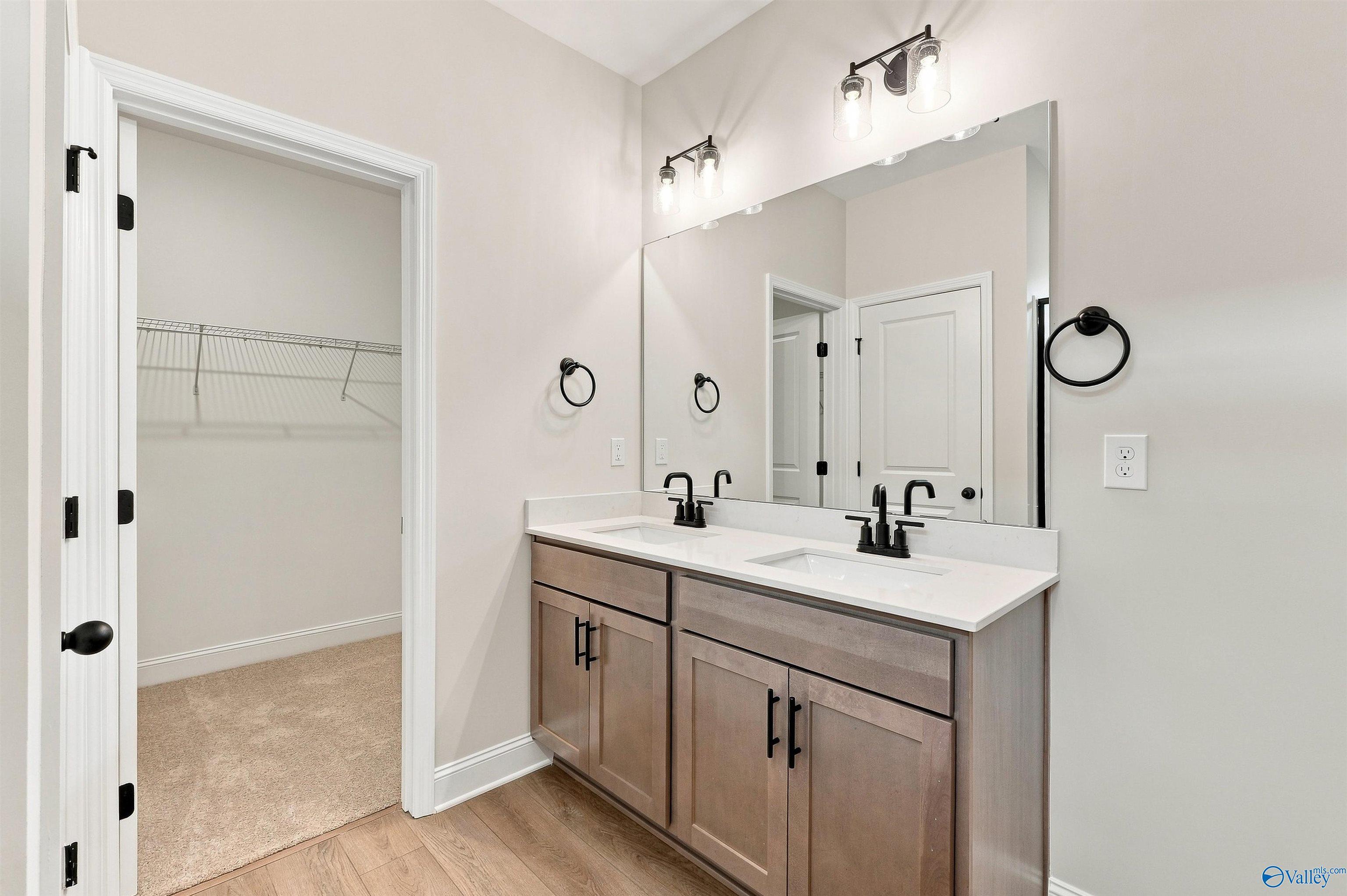 Double vanity bathroom with wood cabinets, black fixtures, and walk-in closet in Davidson Homes Franklin C plan, Athens, AL