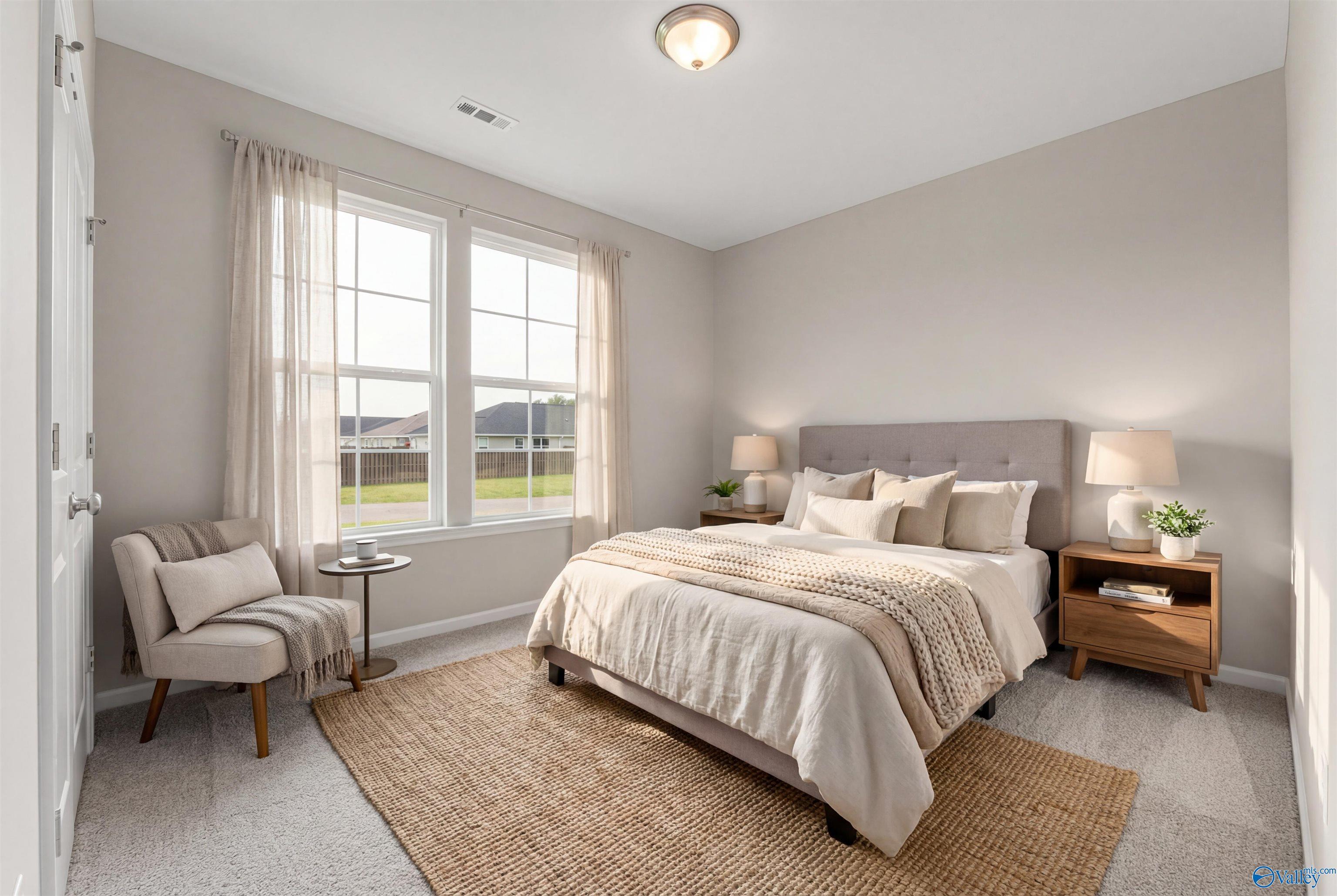 Serene bedroom with neutral beige walls, plush bed, armchair, and large sunny windows in Davidson Homes The Phoenix, Fayetteville, TN