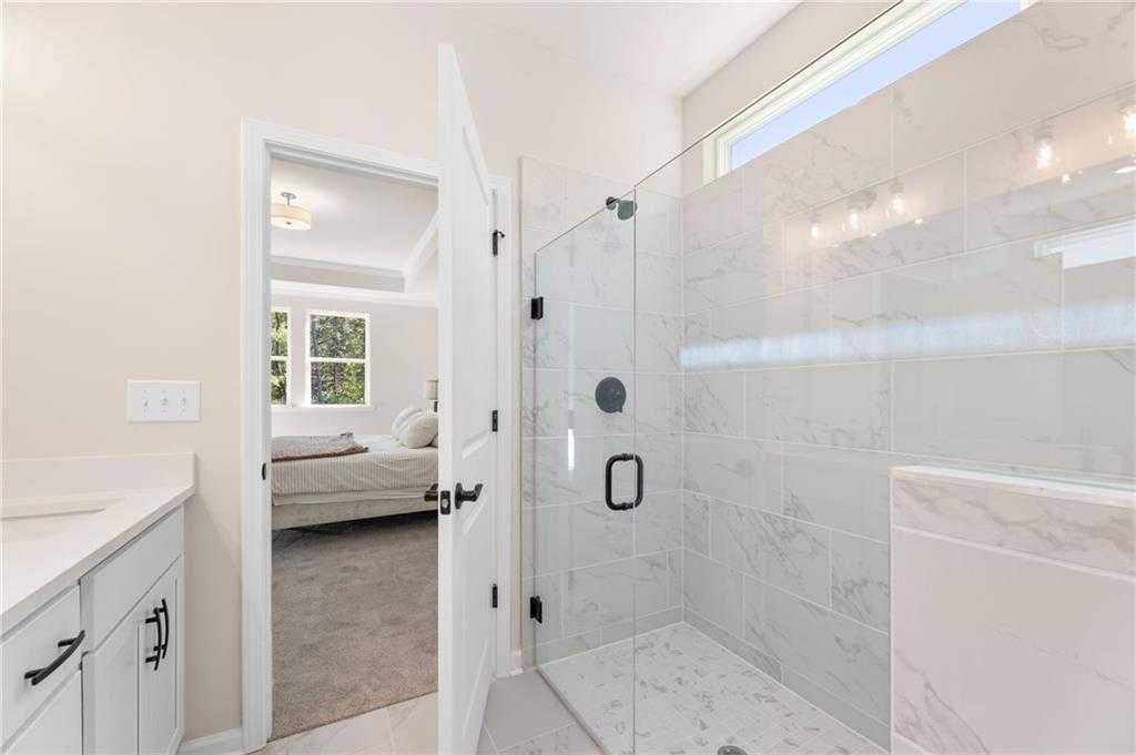 Modern master bathroom with frameless glass shower, white subway tile, and adjacent bedroom in Davidson Homes The Daphne B, Loganville, GA