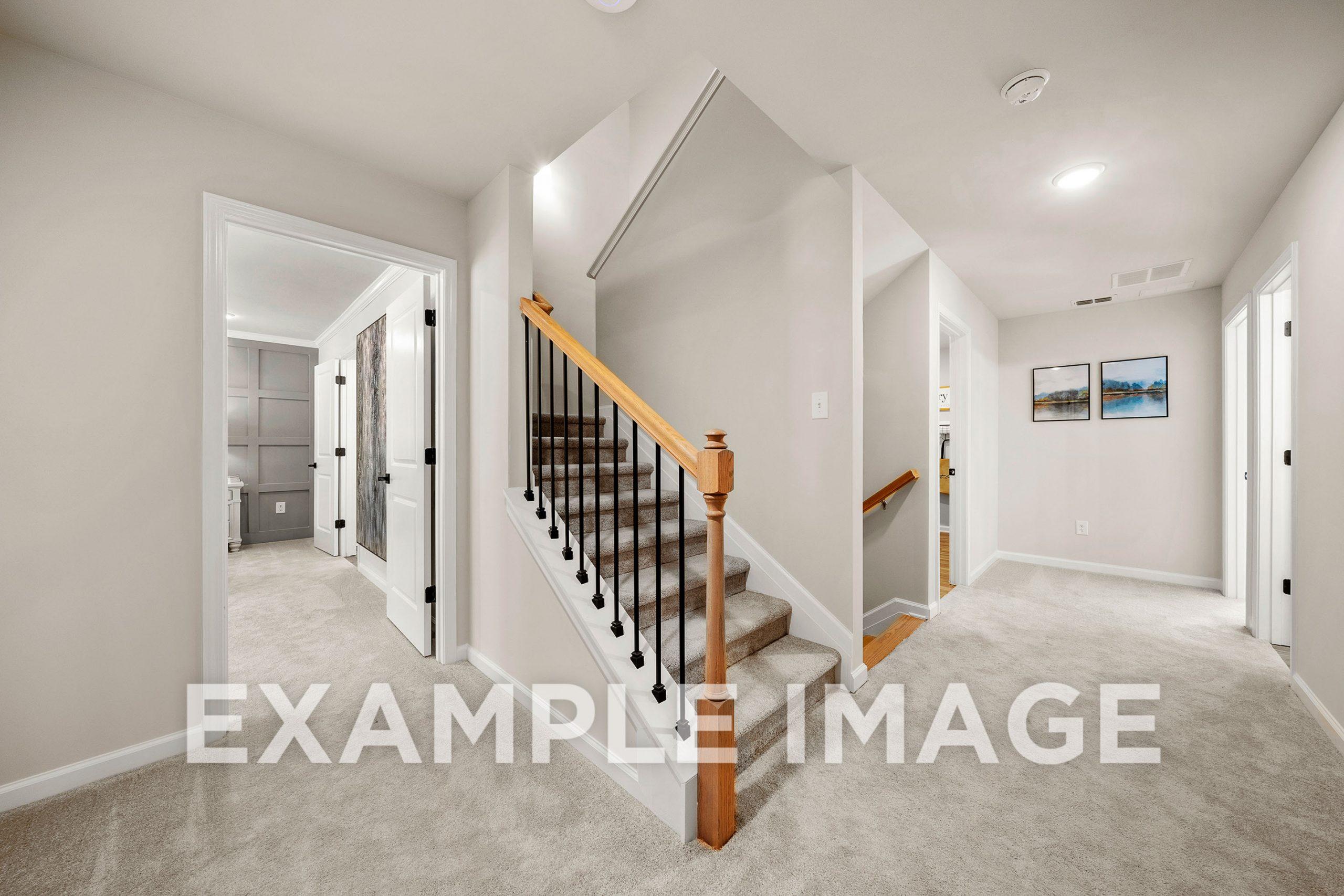 Spacious upper floor hallway in The Hickory B with oak staircase, beige walls, carpeted floors, and bedroom doors