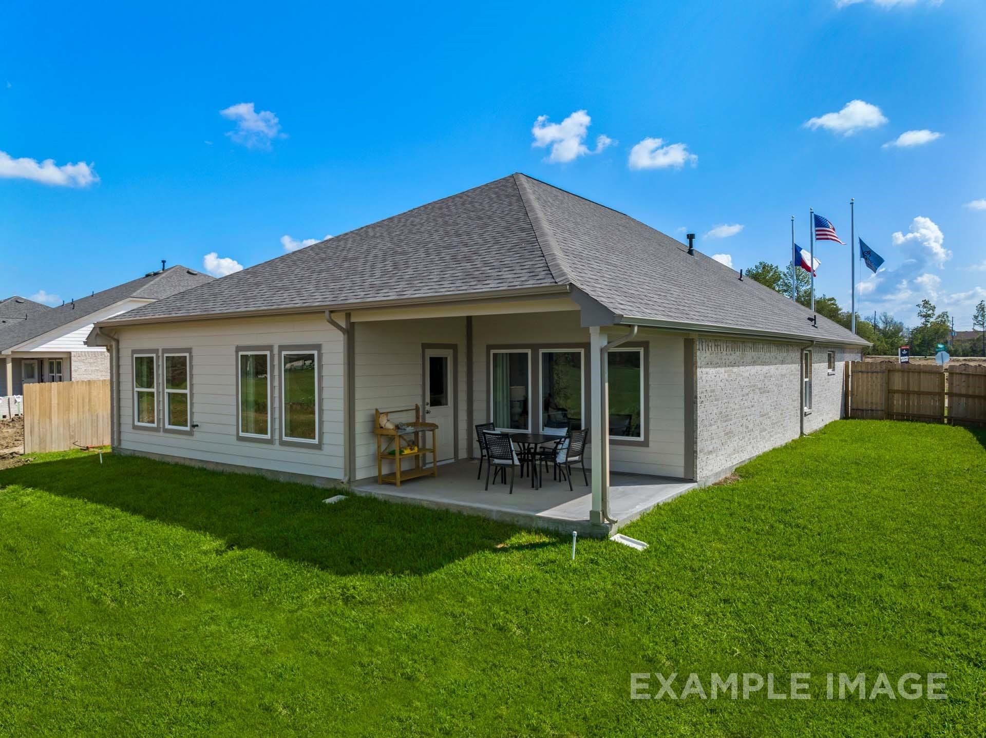 Side view of Davidson Homes The Acadia A 4-bedroom single-story with covered patio, outdoor seating, and lush green lawn in Lago Mar, Texas City