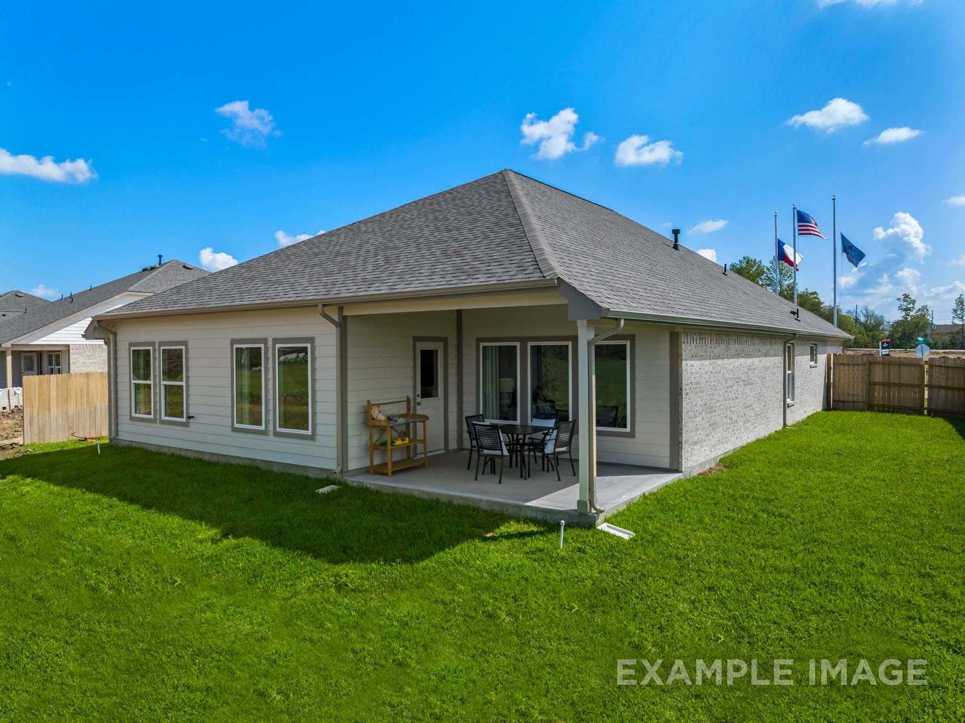 Covered patio with wooden seating on lush green lawn beside single-story 4-bedroom Davidson Homes in Lago Mar, Texas City