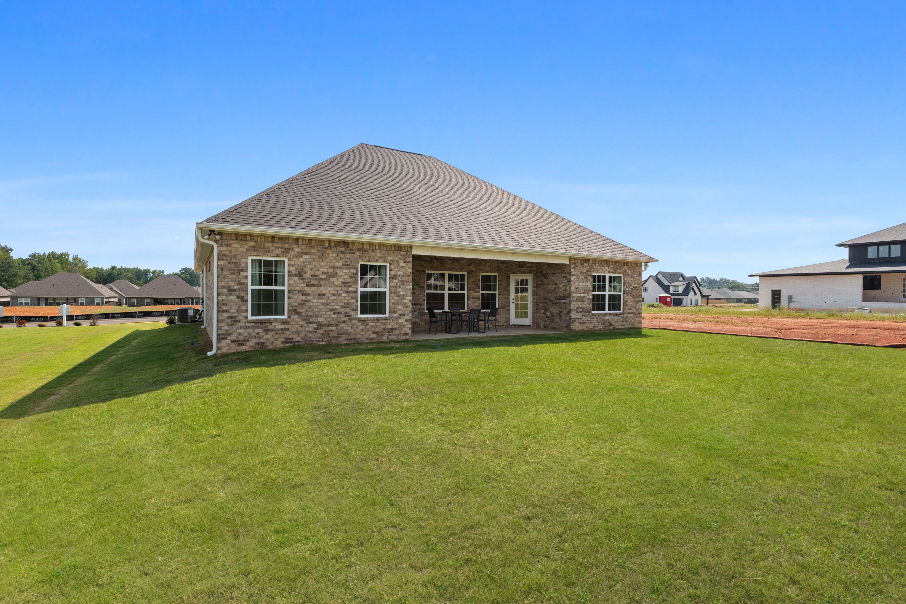 Brick home exterior with covered back patio and seating at River Road Estates in Decatur, Alabama surrounded by lush green lawn