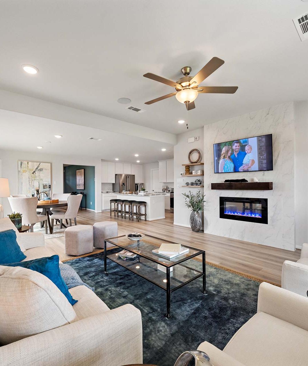 Open-concept living room in Sunterra Katy Texas by Davidson Homes with gas fireplace TV dining area and modern seating