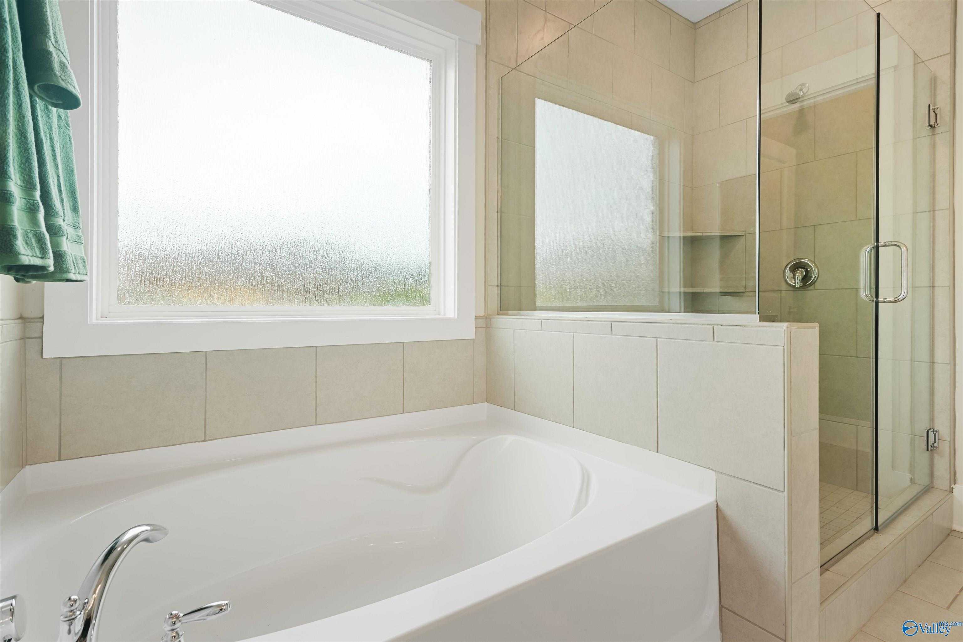 Elegant master bathroom featuring freestanding tub and glass shower with frosted window in Davidson Homes The Daphne, Harvest AL