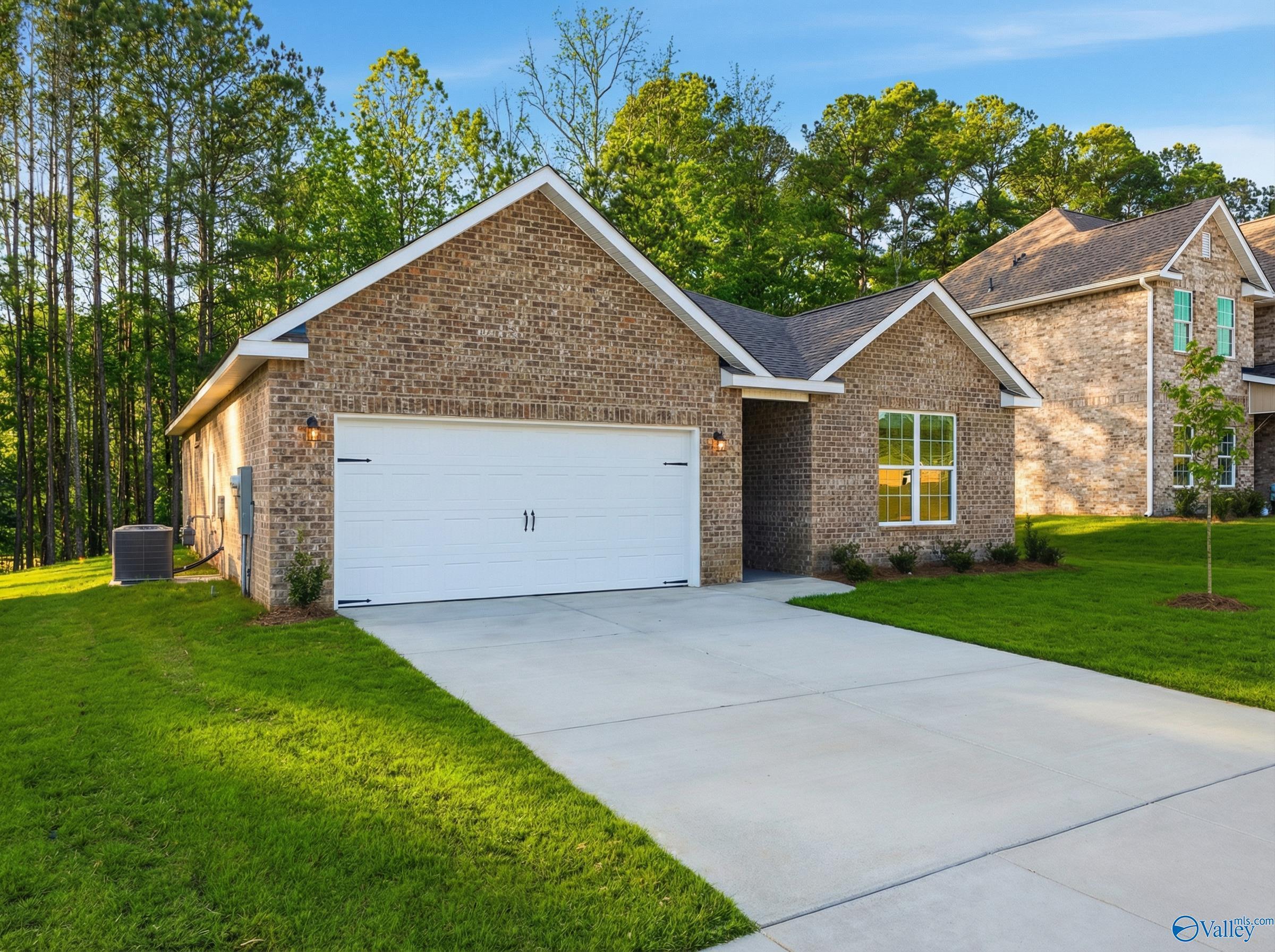Single-story brick home with 2-car garage, lush lawn, and pine trees in The Highlands, Arab, Alabama - Davidson Homes The Asheville