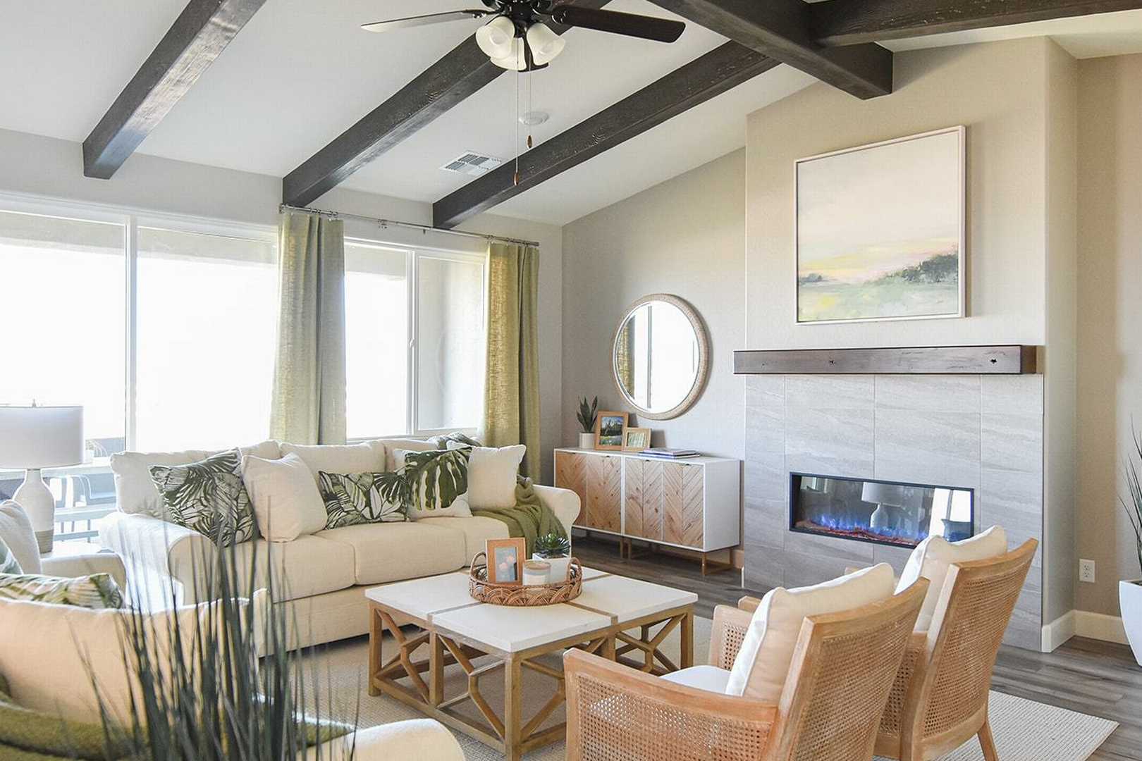 Spacious living room in The Summit B featuring gas fireplace, beamed ceiling, neutral tones, and tropical accents