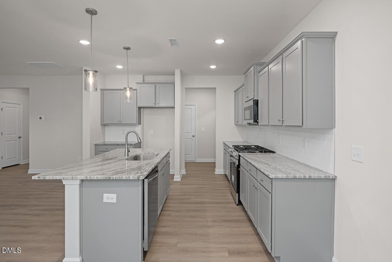 Modern gray kitchen island with white quartz counters, stainless appliances in The Gavin B by Davidson Homes, Lillington, NC