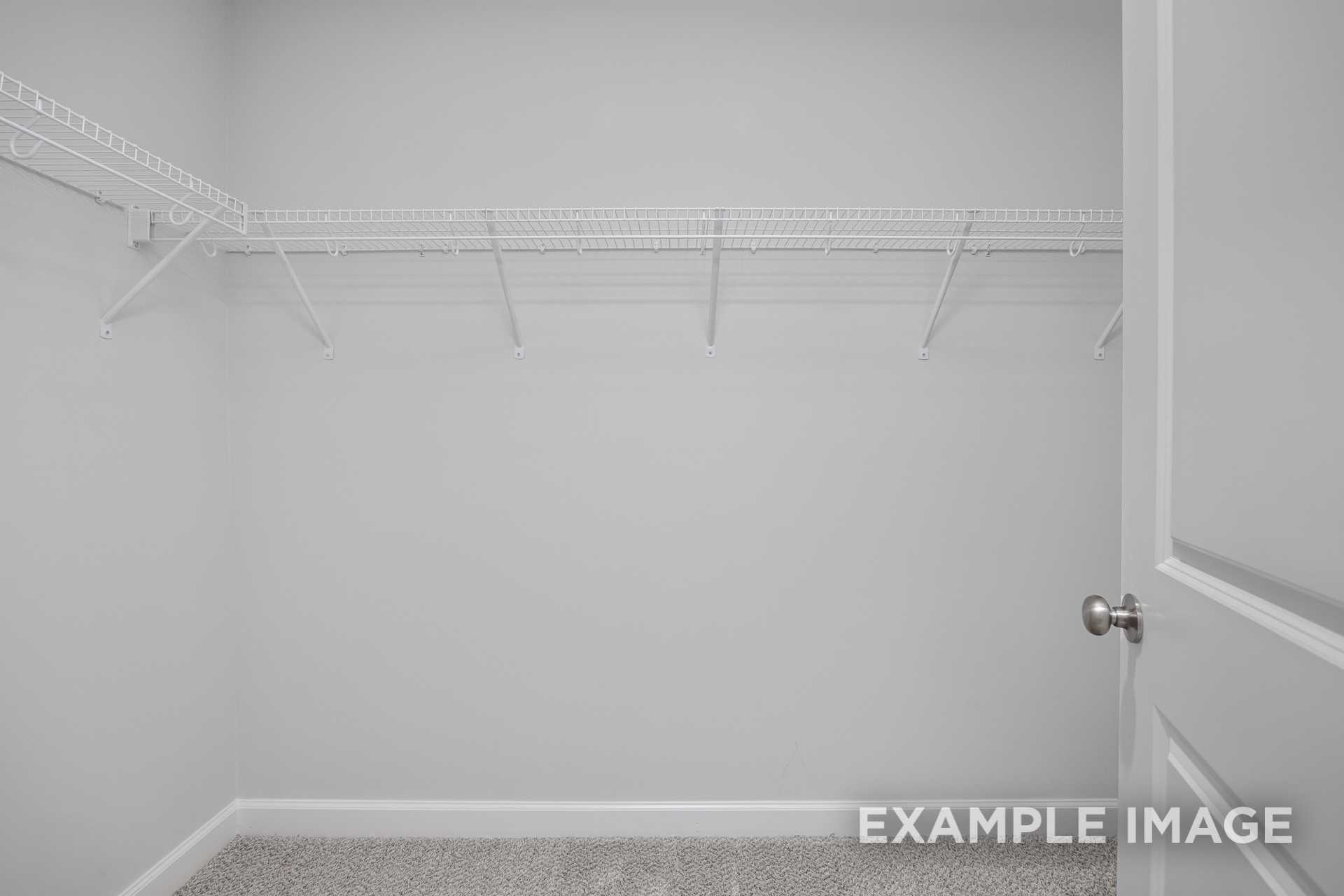Spacious walk-in closet in The Grace C master suite featuring white wire shelving, neutral walls, and carpeted floor