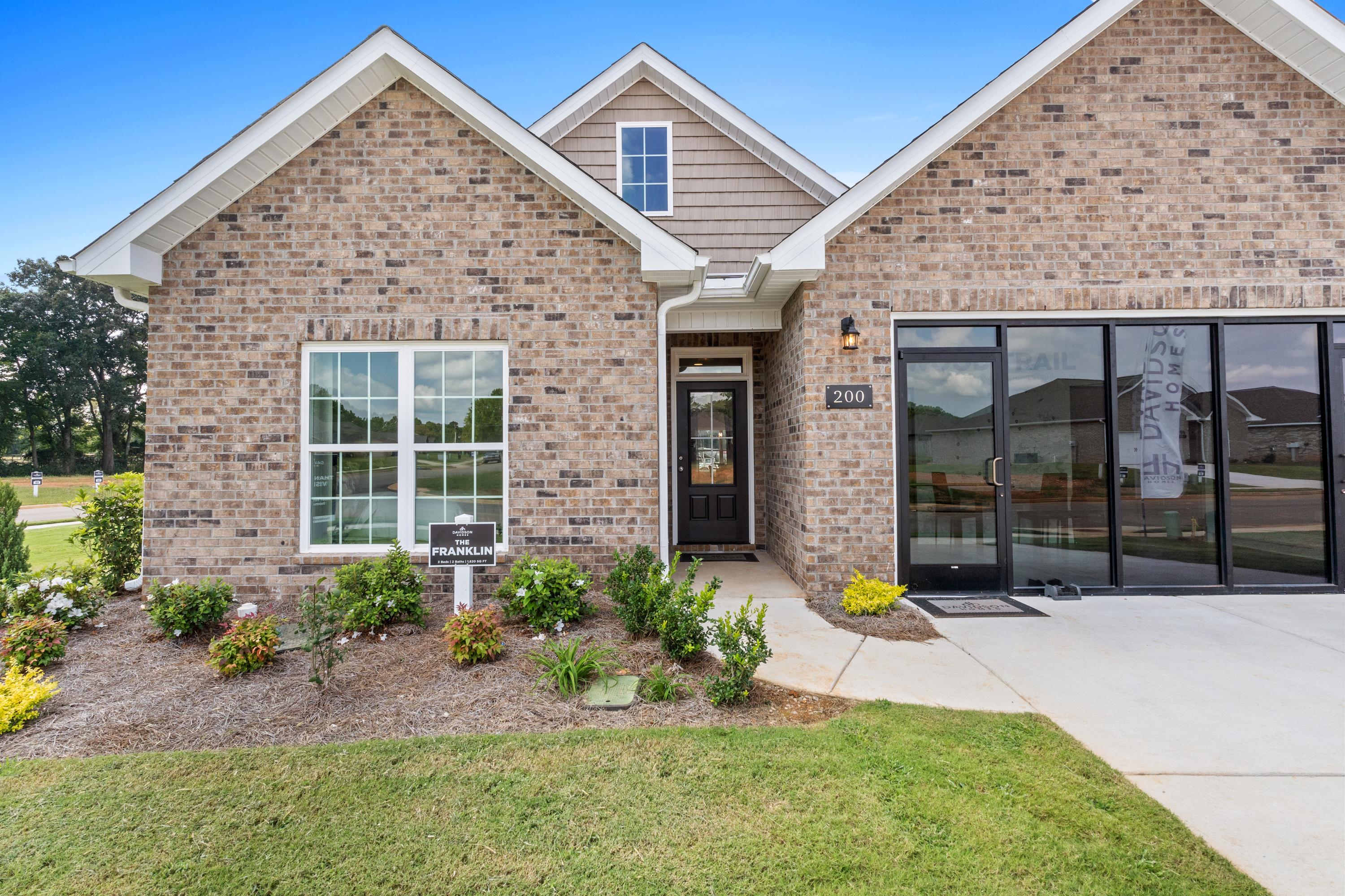 Brick Craftsman home exterior at Wood Trail in Toney, Alabama with gabled roof, front porch, and landscaped yard