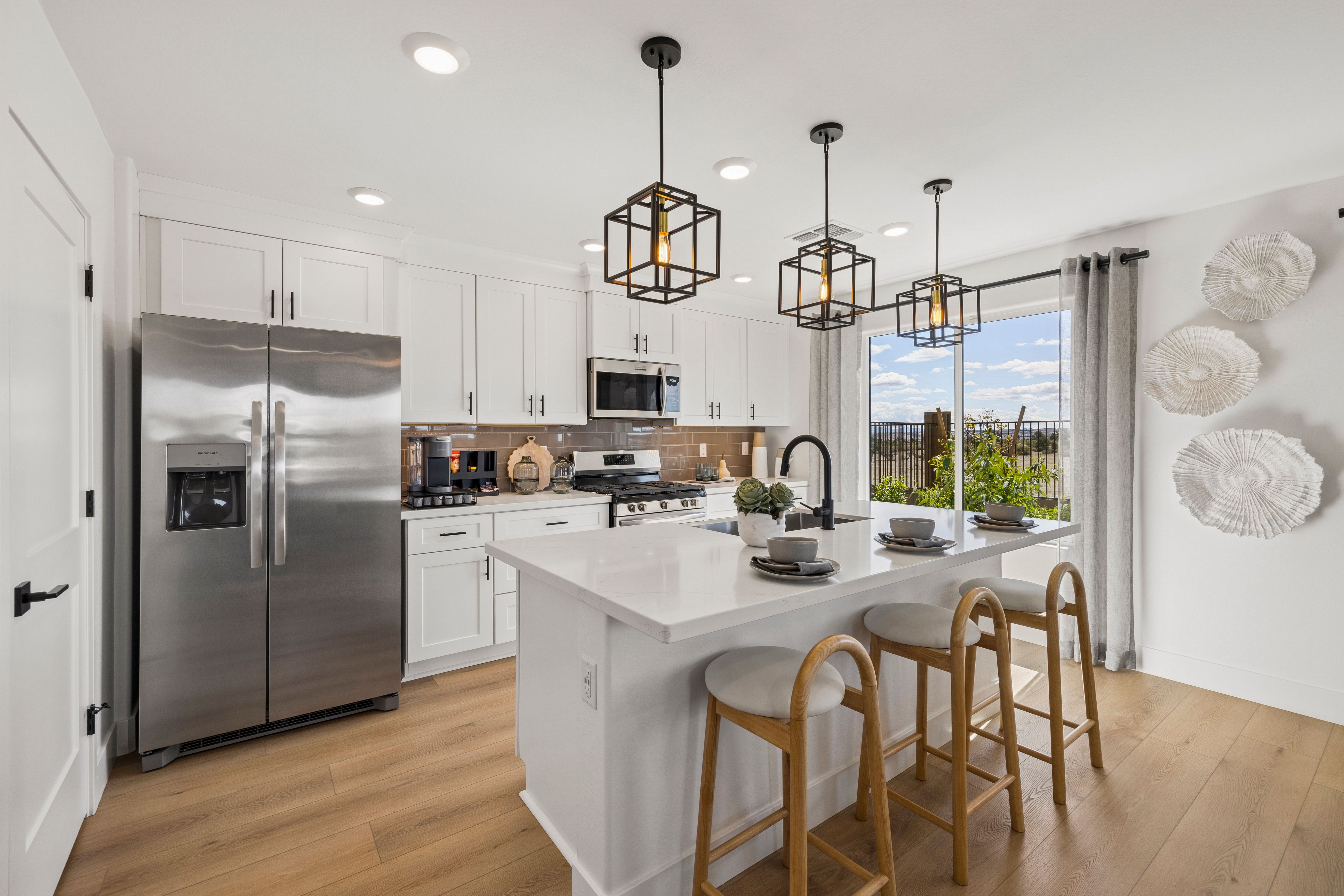 Modern kitchen at South Ranch Southern Collection in Prescott AZ with white cabinets, quartz island, bar stools, and scenic window view