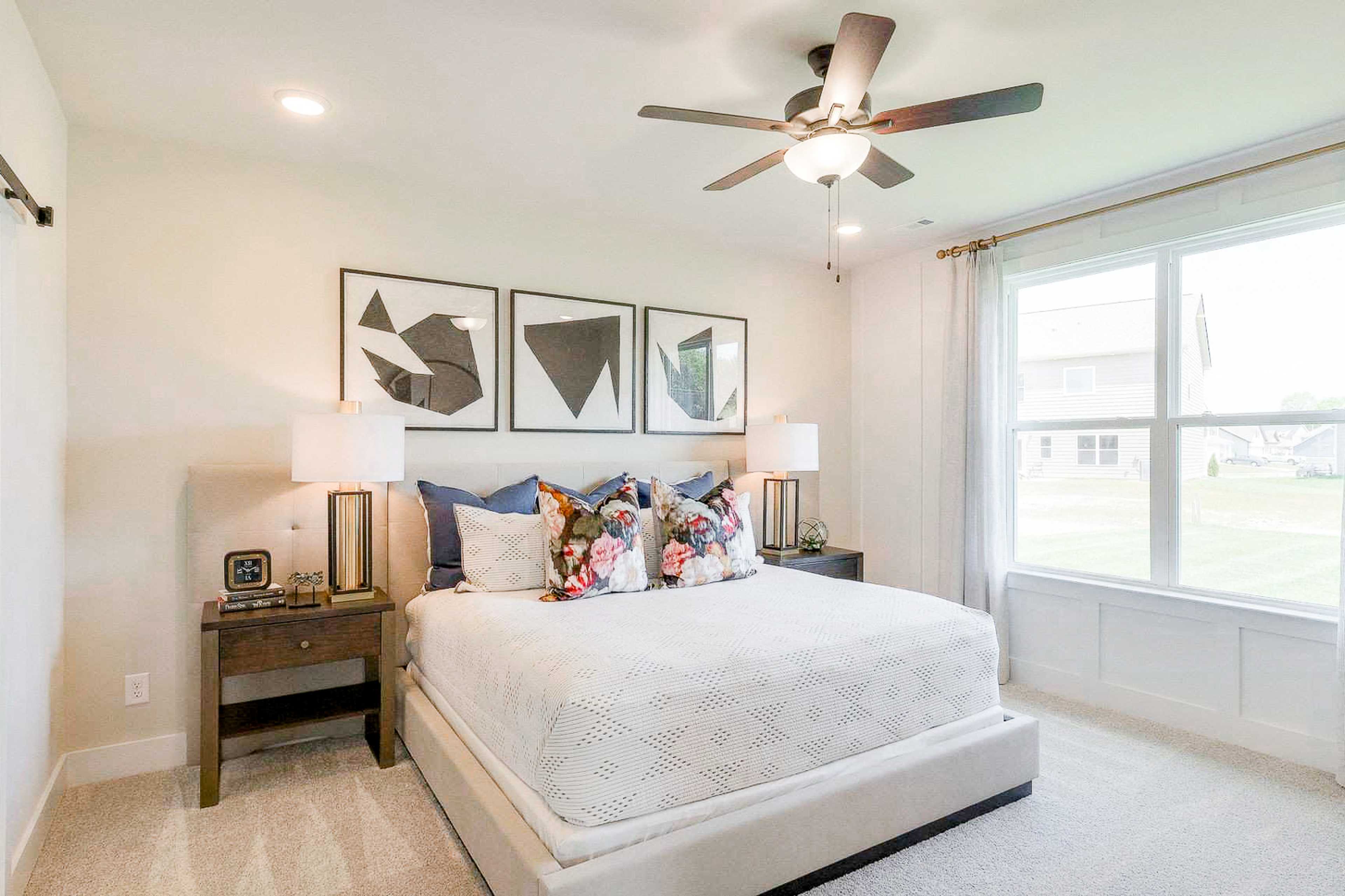 Spacious master bedroom at The Meadows in Smyrna TN with king bed, abstract art, ceiling fan, and large windows
