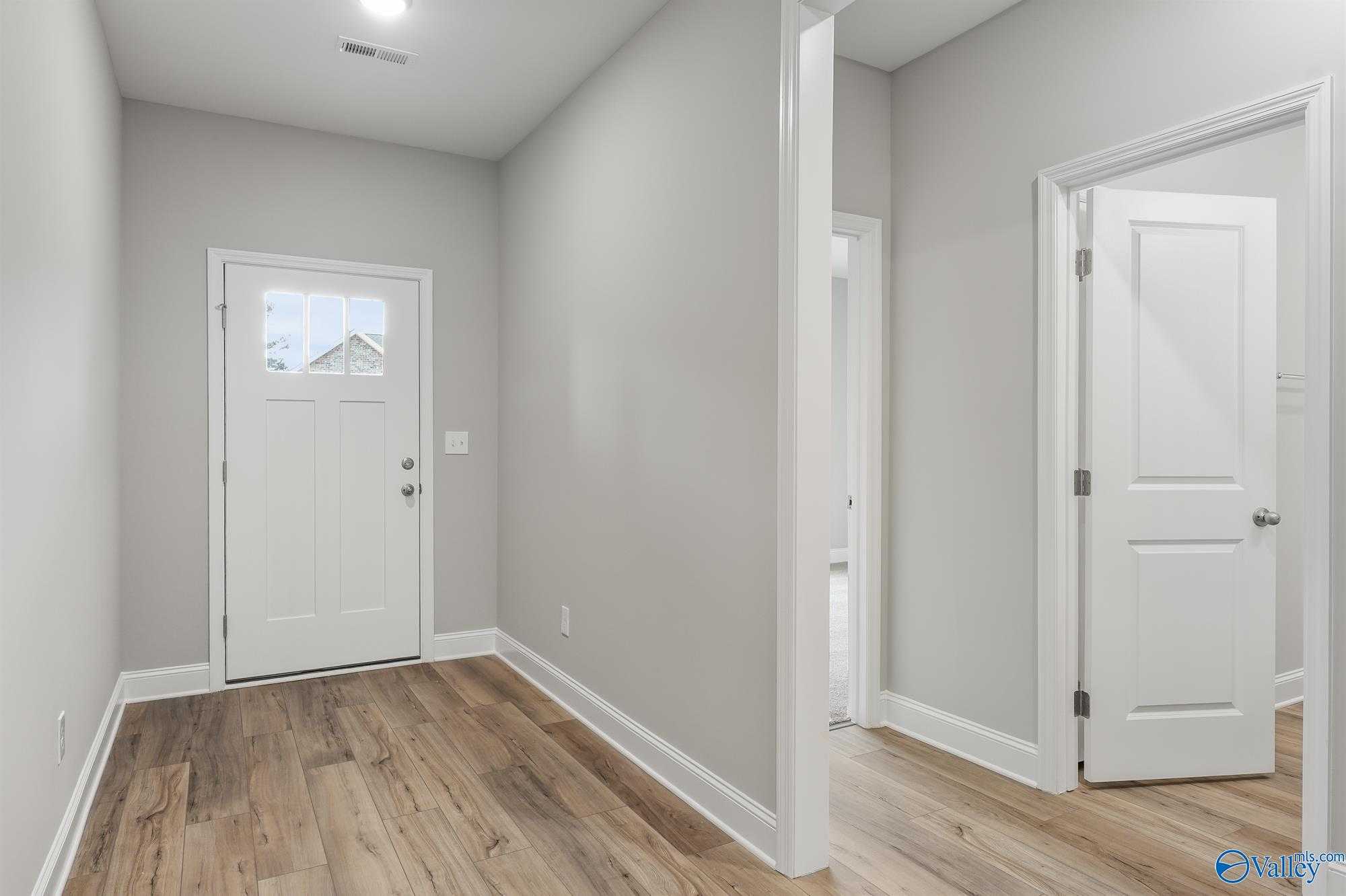 Bright entryway with gray walls, hardwood floors, and white doors in 4-bedroom The Daphne D home, Davidson Homes, Athens, Alabama