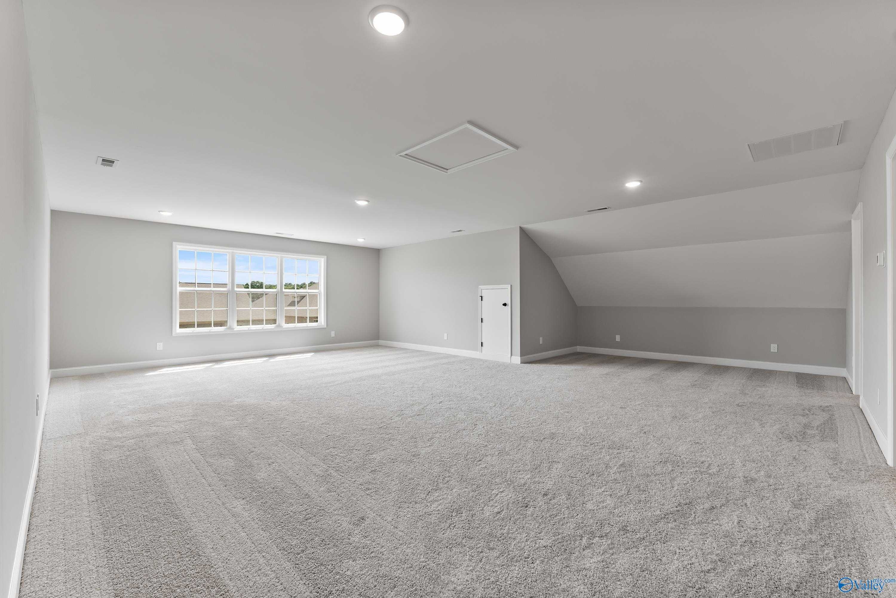 Spacious bonus room with sloped ceiling, large triple window and gray carpet in Davidson Homes The Montgomery B With Bonus, Toney, Alabama