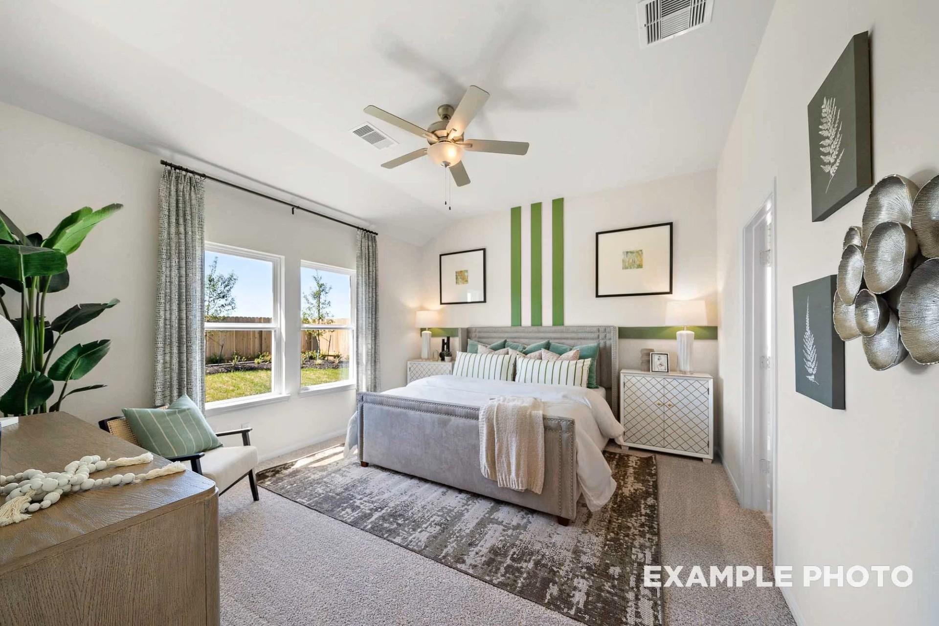 Elegant master bedroom with king bed, ceiling fan, and backyard views in Davidson Homes The Tierra B, Beasley, Texas