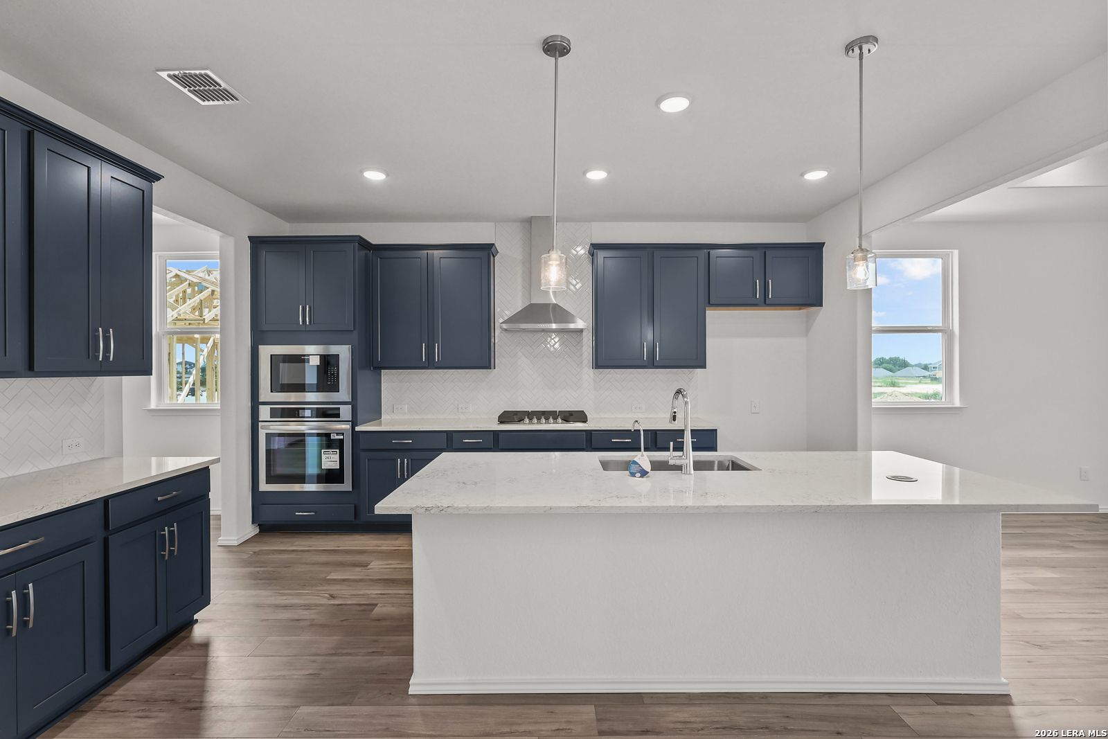 Modern kitchen featuring navy cabinets, white quartz island, stainless appliances in Davidson Homes The Glenwood E, Elmendorf TX