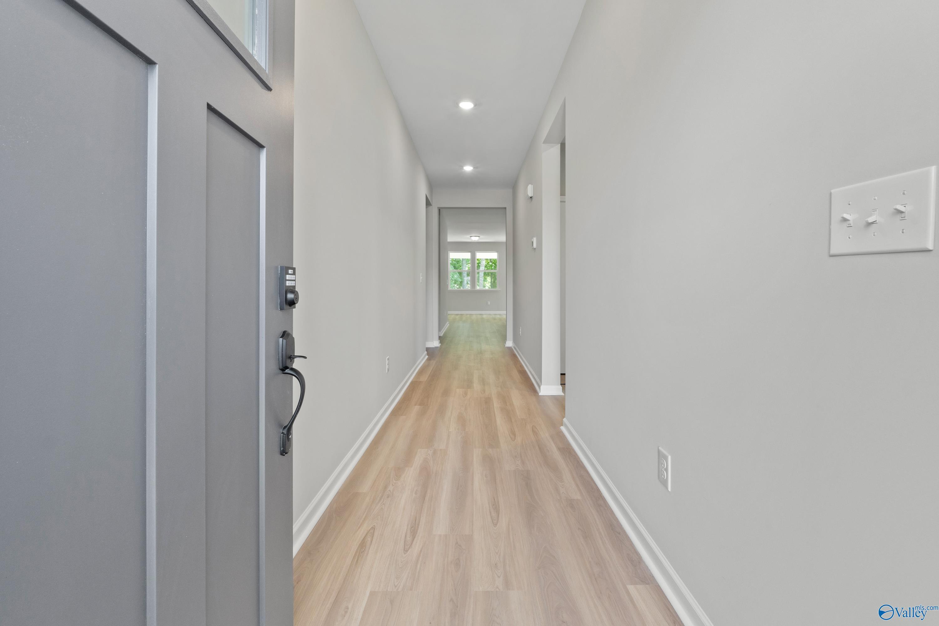 Bright hallway with light oak floors, gray walls, and recessed lighting in The Phoenix 3-bedroom home by Davidson Homes, Fayetteville, TN