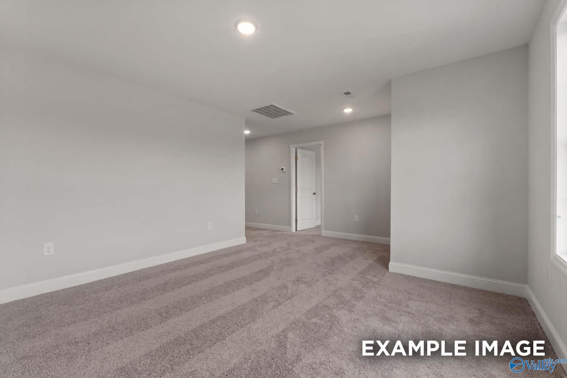Spacious carpeted bedroom with light gray walls, recessed lighting, and open door in Davidson Homes Shelby C, Arab Alabama