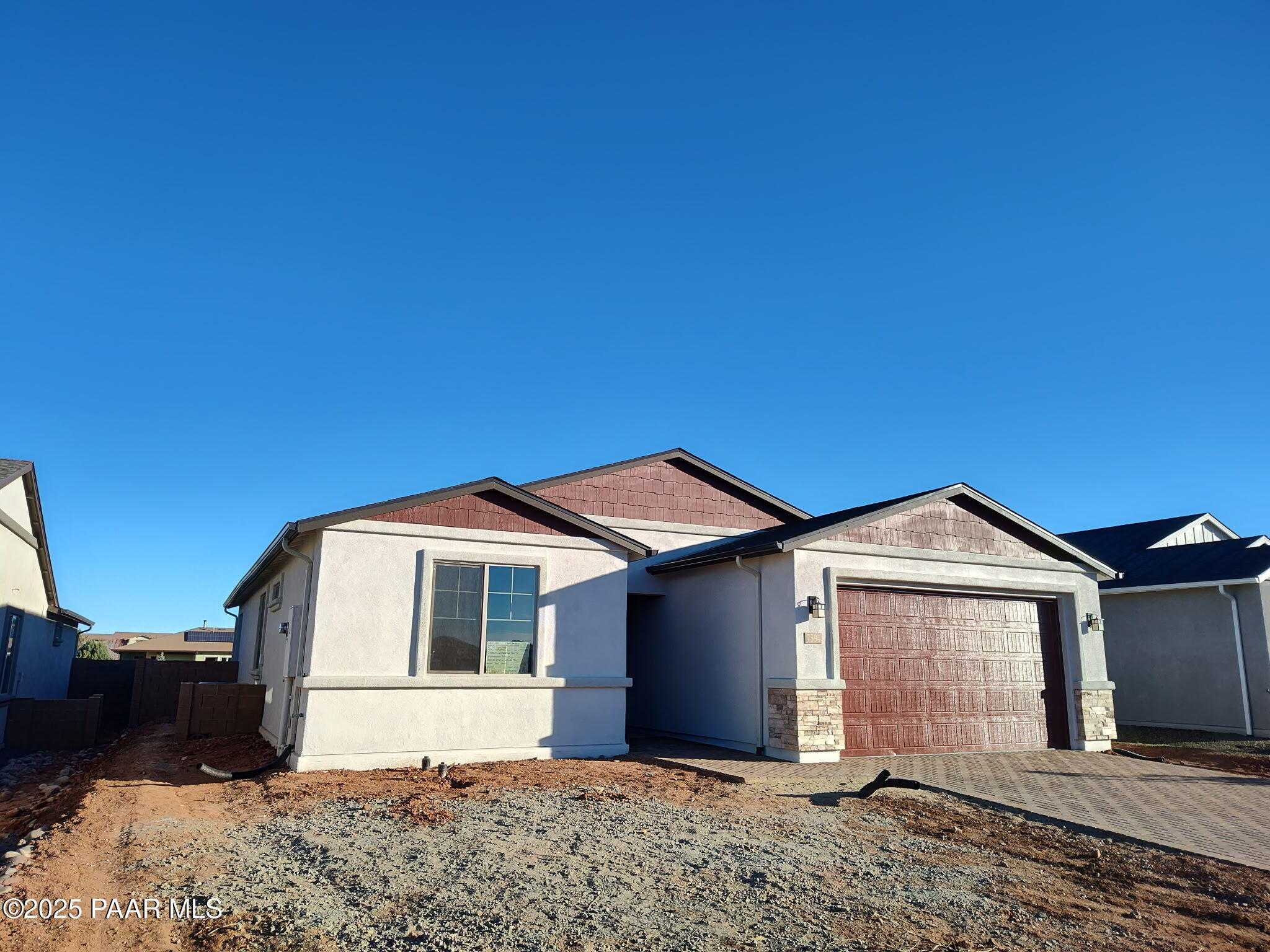 Modern 1-story home exterior with beige stucco, 3-car garage, and brown roof in North Ridge at Pronghorn Ranch, Prescott Valley, Arizona