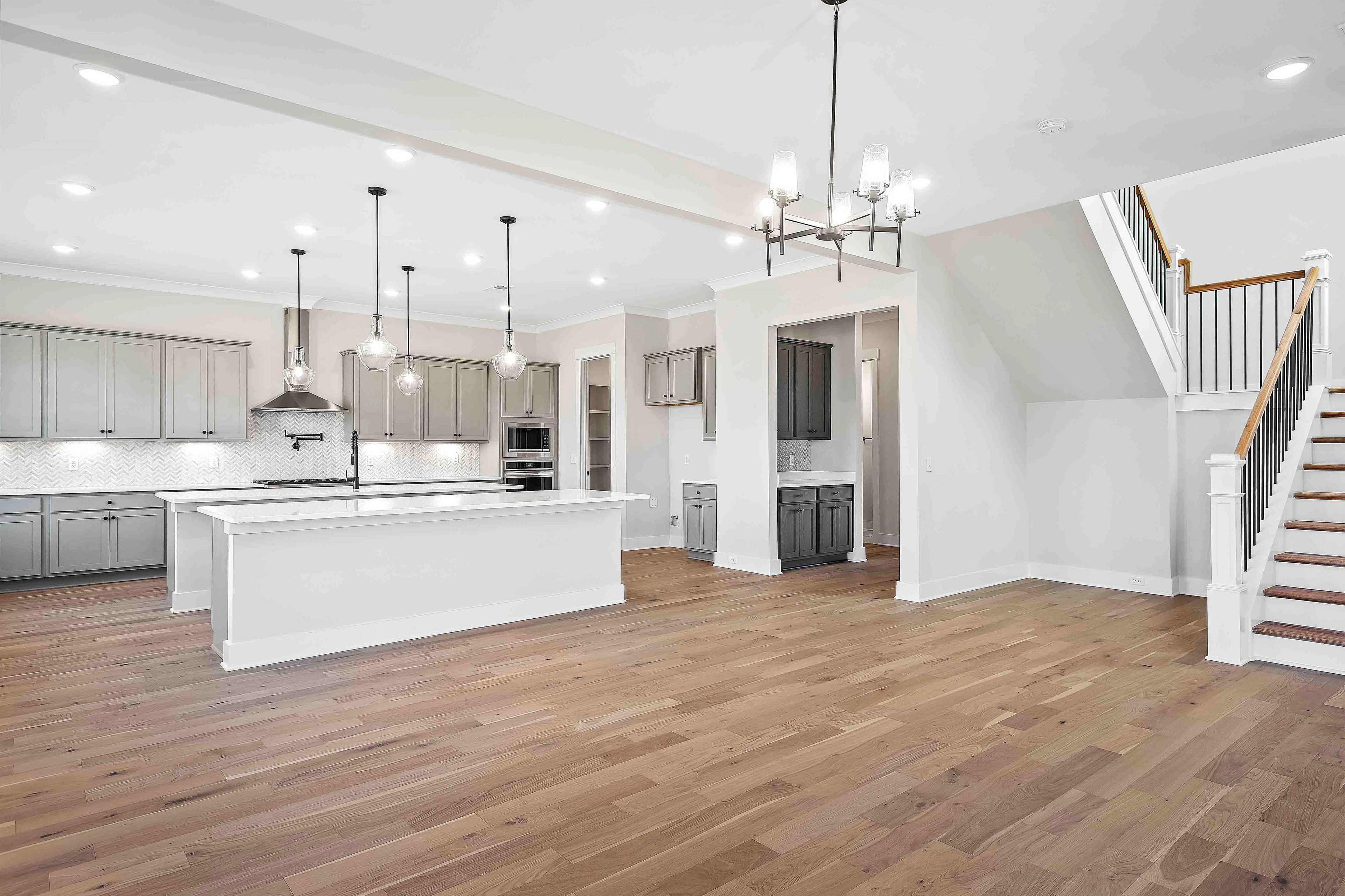 Spacious open-concept kitchen at Shelton Square in Murfreesboro TN with gray cabinets, white island, pendant lights, and hardwood floors