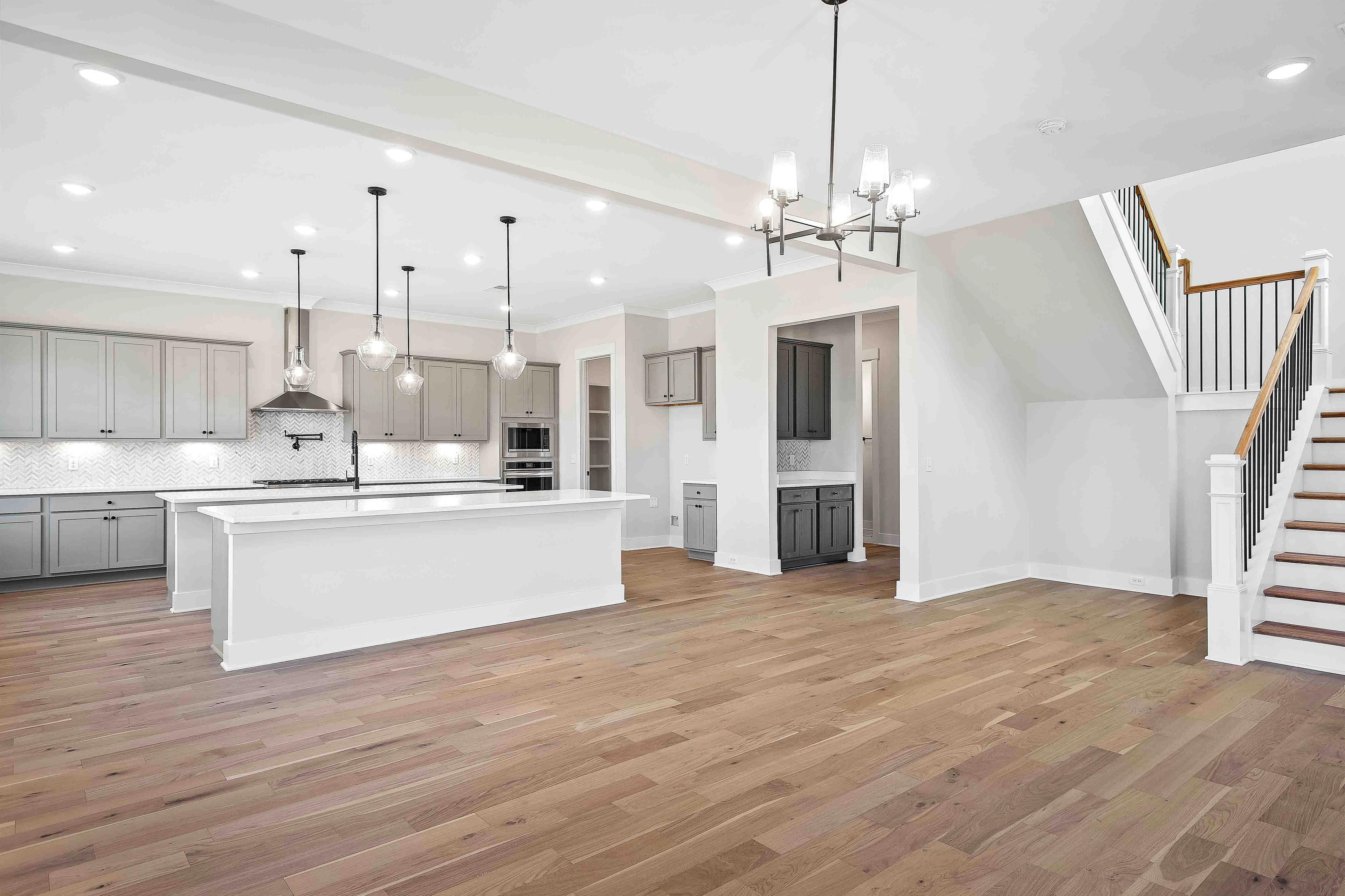 Spacious open-concept kitchen at Shelton Square in Murfreesboro TN with gray cabinets, white island, pendant lights, and hardwood floors