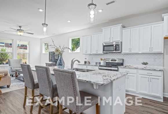 Davidson Homes The Maple Plan Kitchen with white cabinets, appliances, marble countertop, and counter height stools