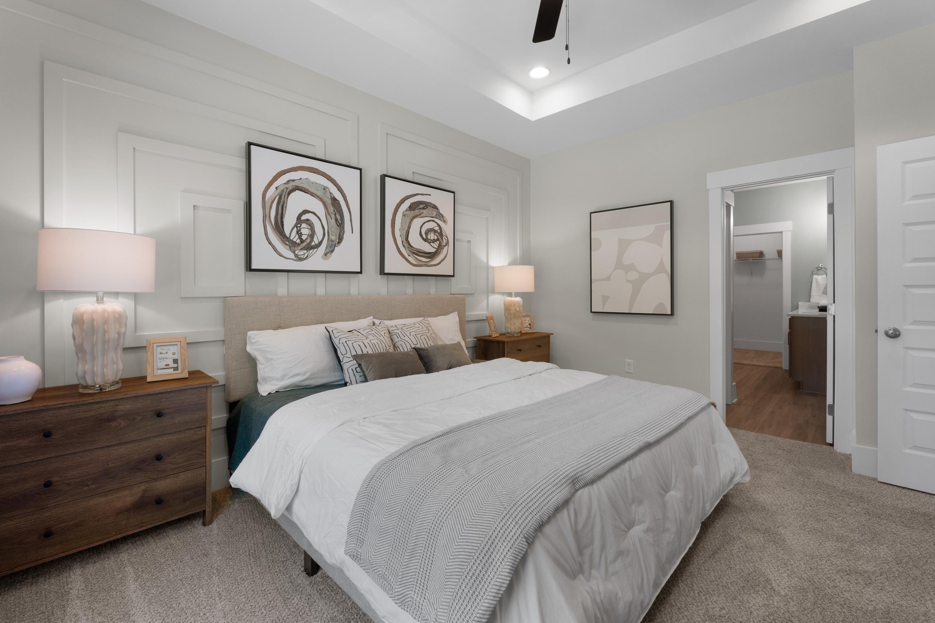 Serene master bedroom in Hollon Meadow Decatur Alabama with gray shiplap walls, king bed, abstract art, and ceiling fan