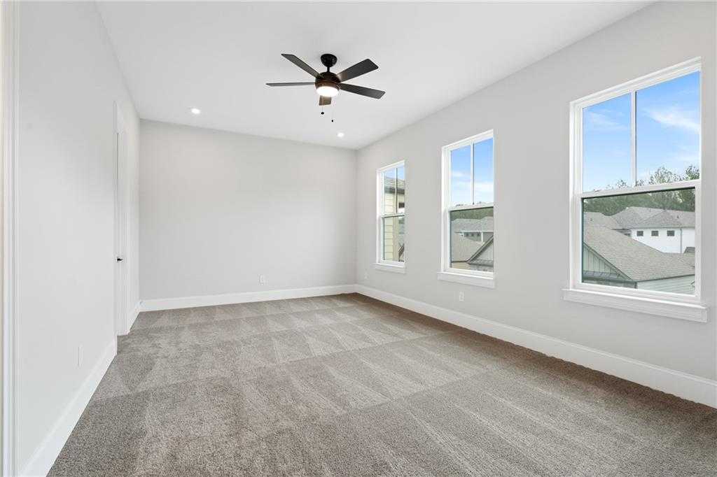 Bright bedroom with light gray walls, large triple windows, ceiling fan, and carpeted floor in Davidson Homes The Seaside B, Woodstock, GA