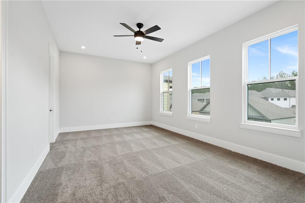 Bright bedroom with light gray walls, large triple windows, ceiling fan, and carpeted floor in Davidson Homes The Seaside B, Woodstock, GA