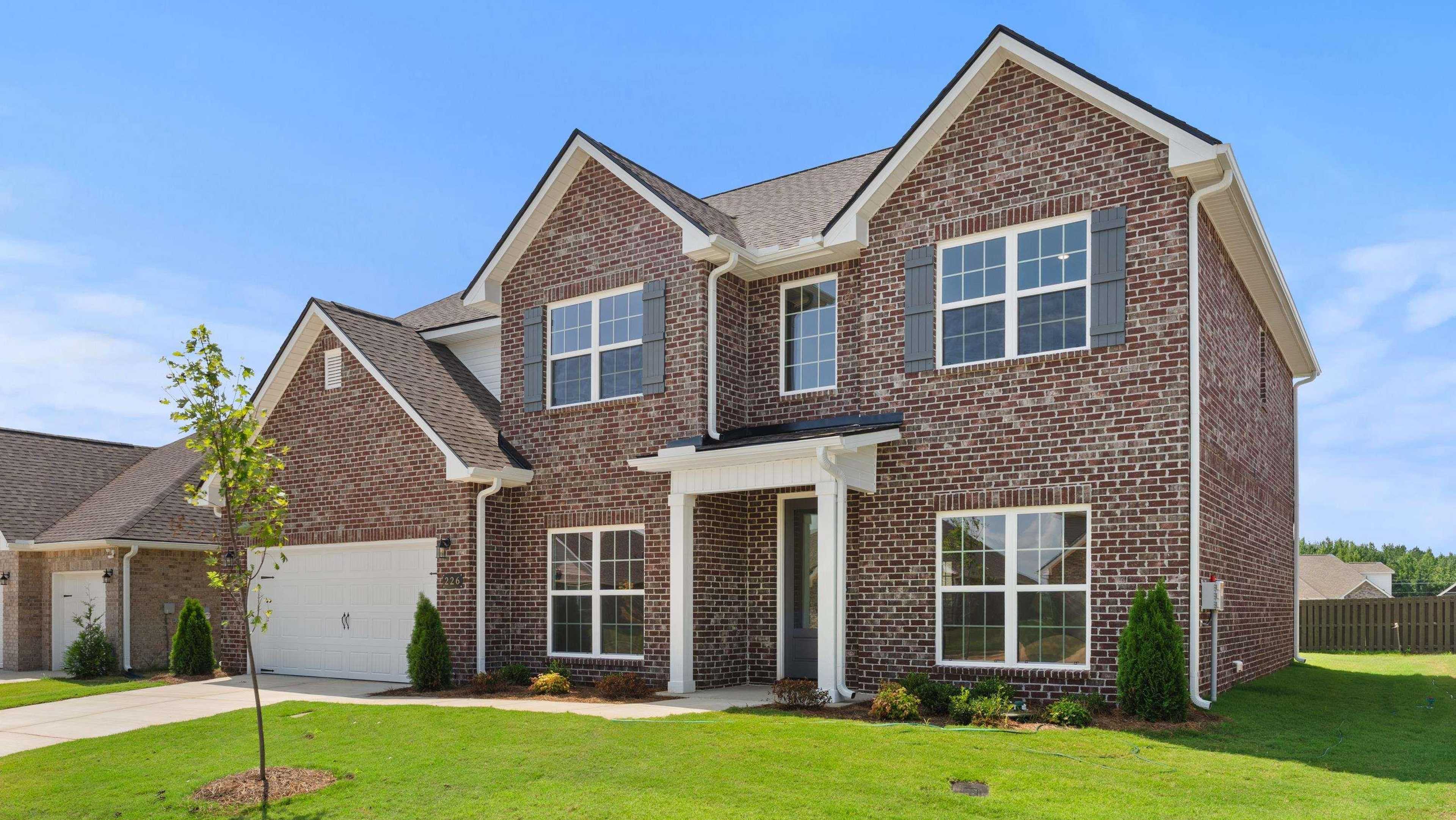 Brick two-story home at Davidson Homes open house, 226 White Horse Way, featuring front porch, garage, and landscaped lawn