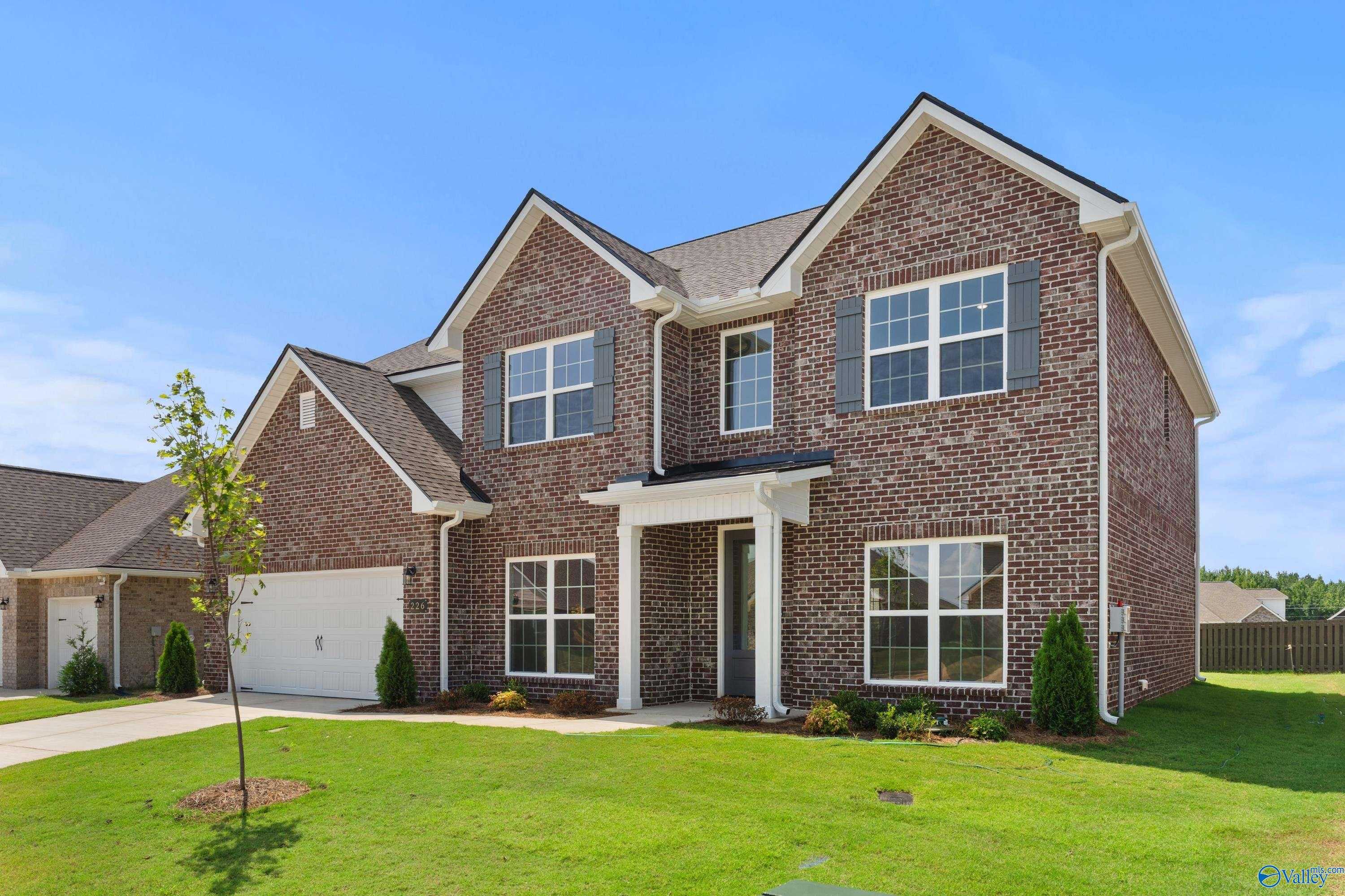 2-story brick home with 2-car garage, gabled roof, front porch, and lush lawn in Kendall Downs, Toney, Alabama