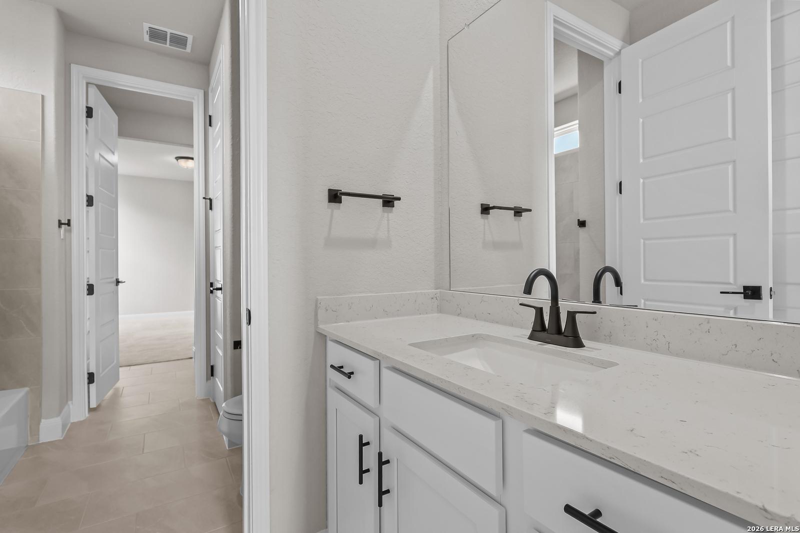 Bathroom with white vanity, quartz countertop, and matte black fixtures in Davidson Homes The Foster E, Potranco Oaks, Castroville, TX