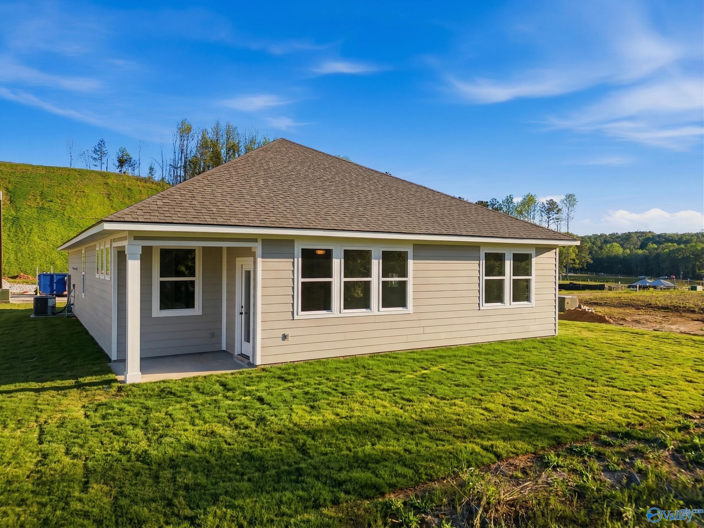 Single-story beige home with gabled roof, covered porch, large windows, and green lawn in Noble Ridge, Cullman, Alabama - Davidson Homes The Laurel K
