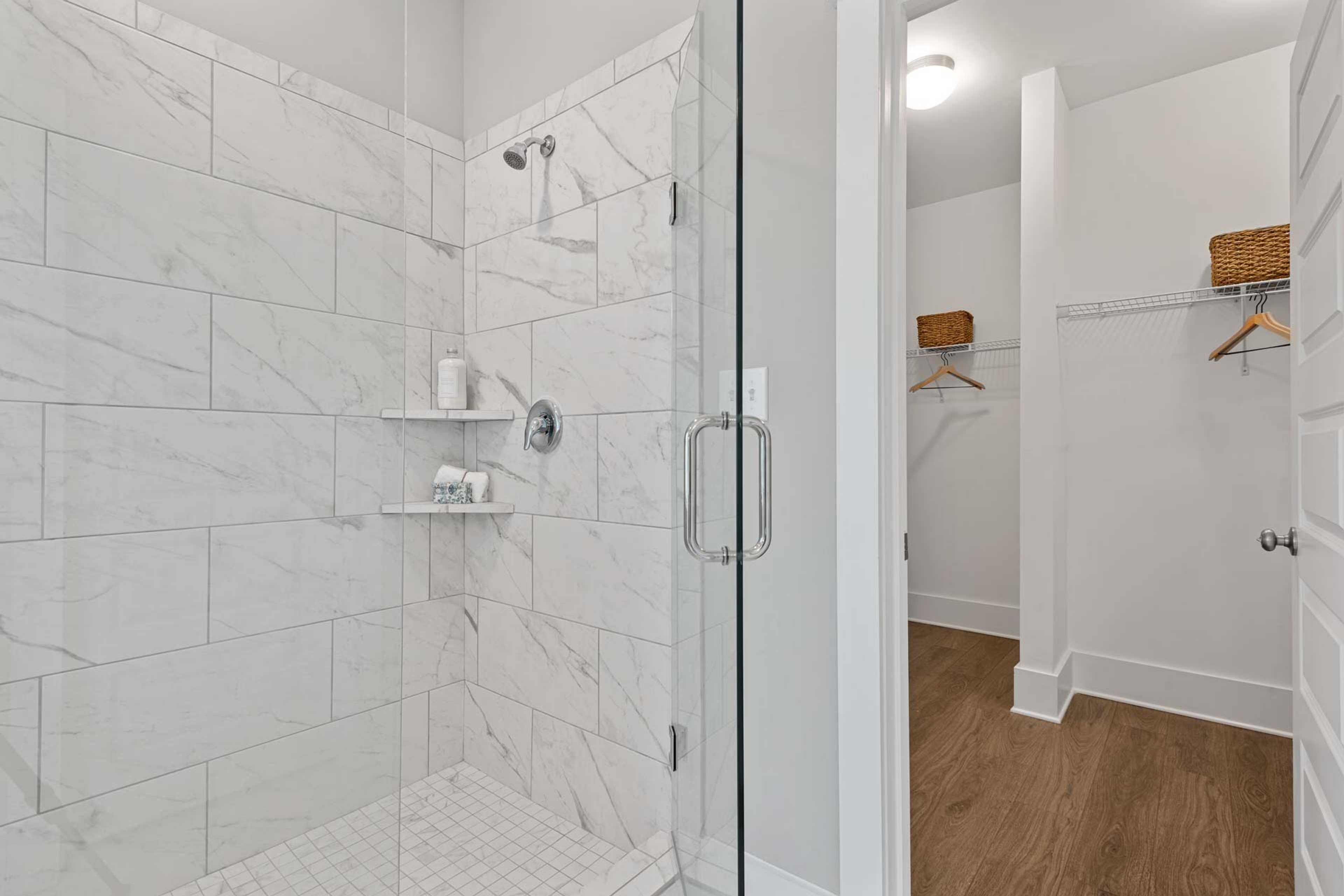 Spacious primary bathroom at Monteagle Cove in Owens Cross Roads Alabama with frameless glass walk-in shower and adjacent closet