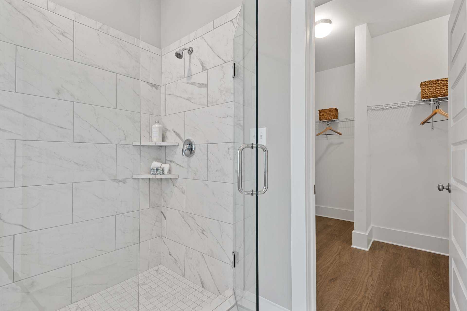 Spacious primary bathroom at Monteagle Cove in Owens Cross Roads Alabama with frameless glass walk-in shower and adjacent closet