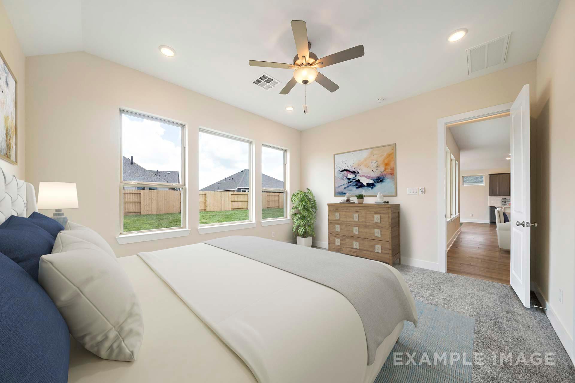 Spacious master bedroom in The Diana C by Davidson Homes with king bed, ceiling fan, large windows overlooking backyard, beige walls