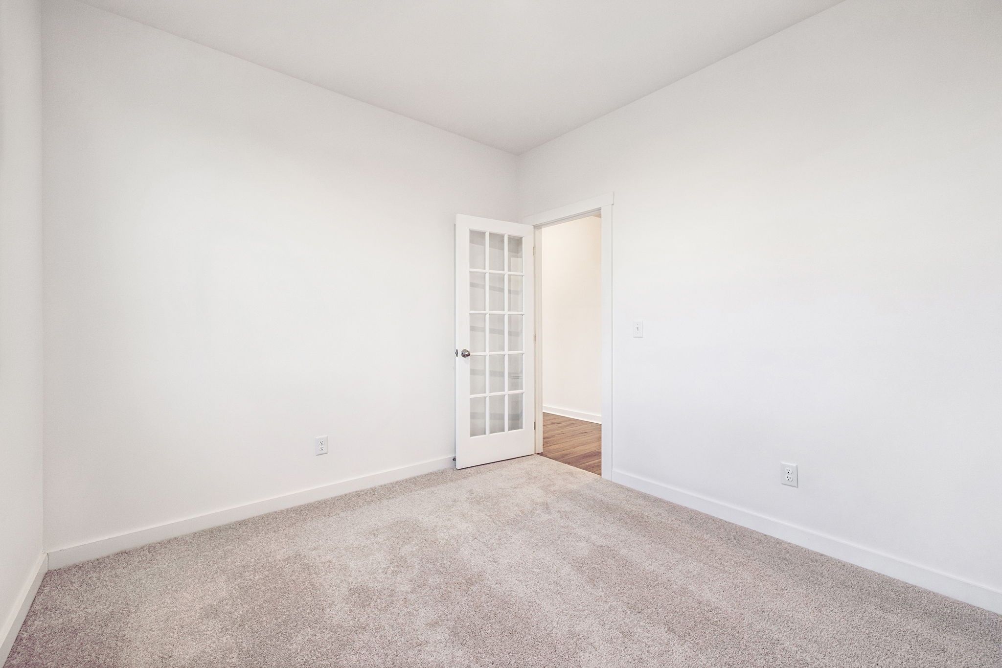 Empty bedroom with French doors, beige carpet, and white walls in Davidson Homes The Willow, Calista Farms, White House, TN